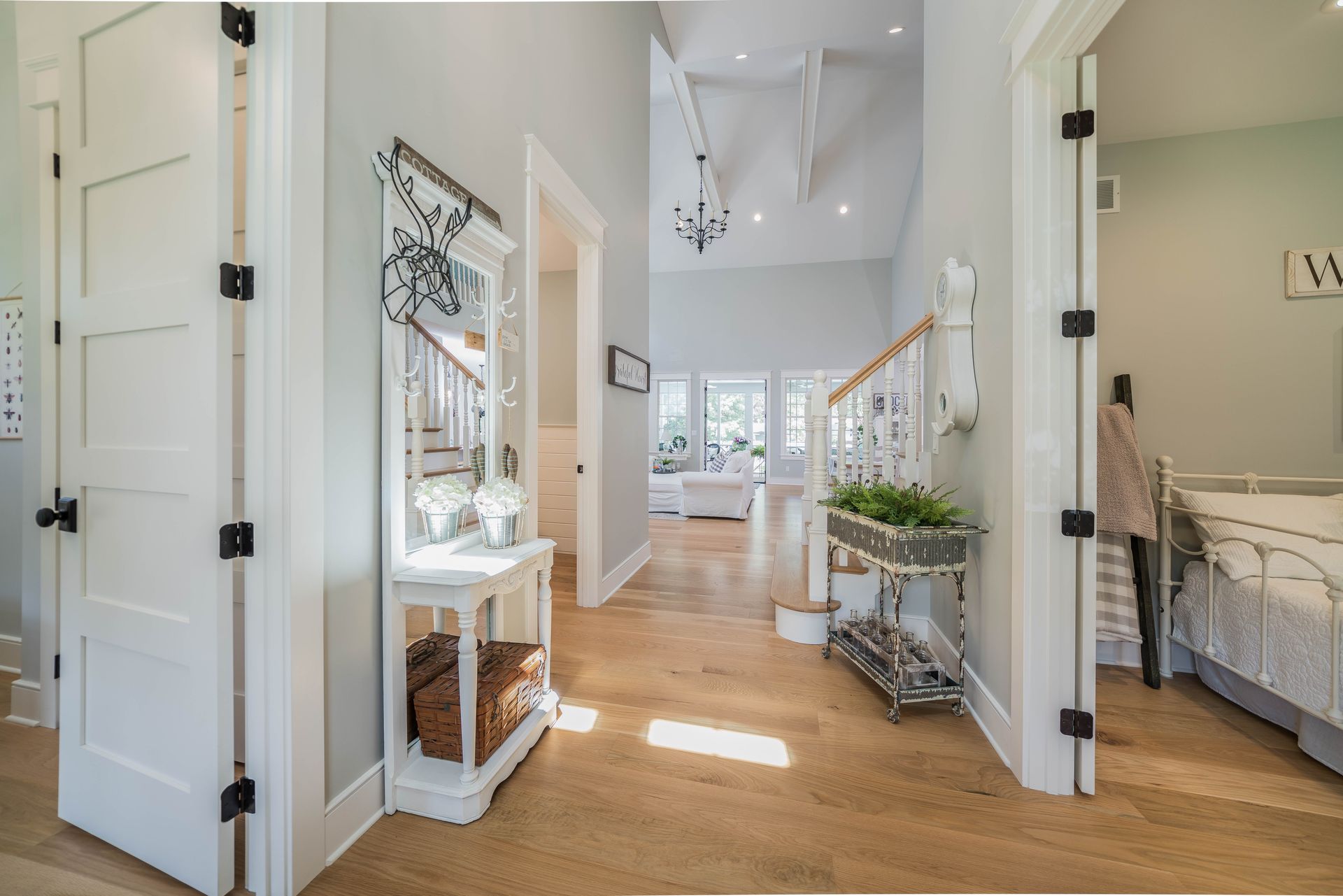 A hallway in a house with hardwood floors and white doors leading to a bedroom.