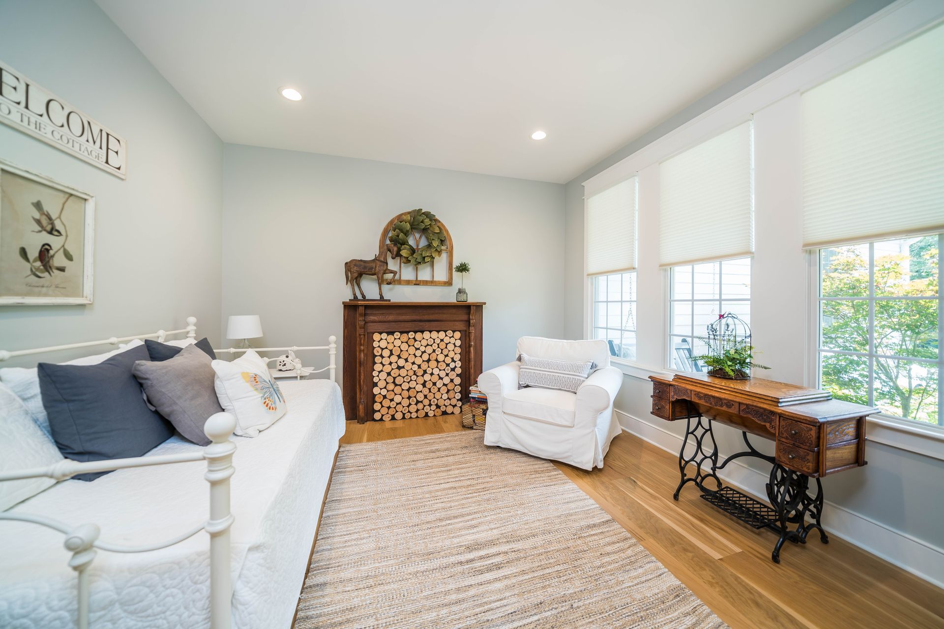 A living room with a day bed , chair , sewing machine and fireplace.