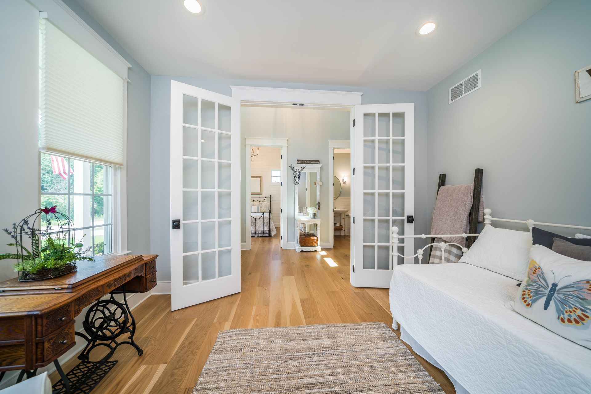 A bedroom with a day bed , desk , and french doors.