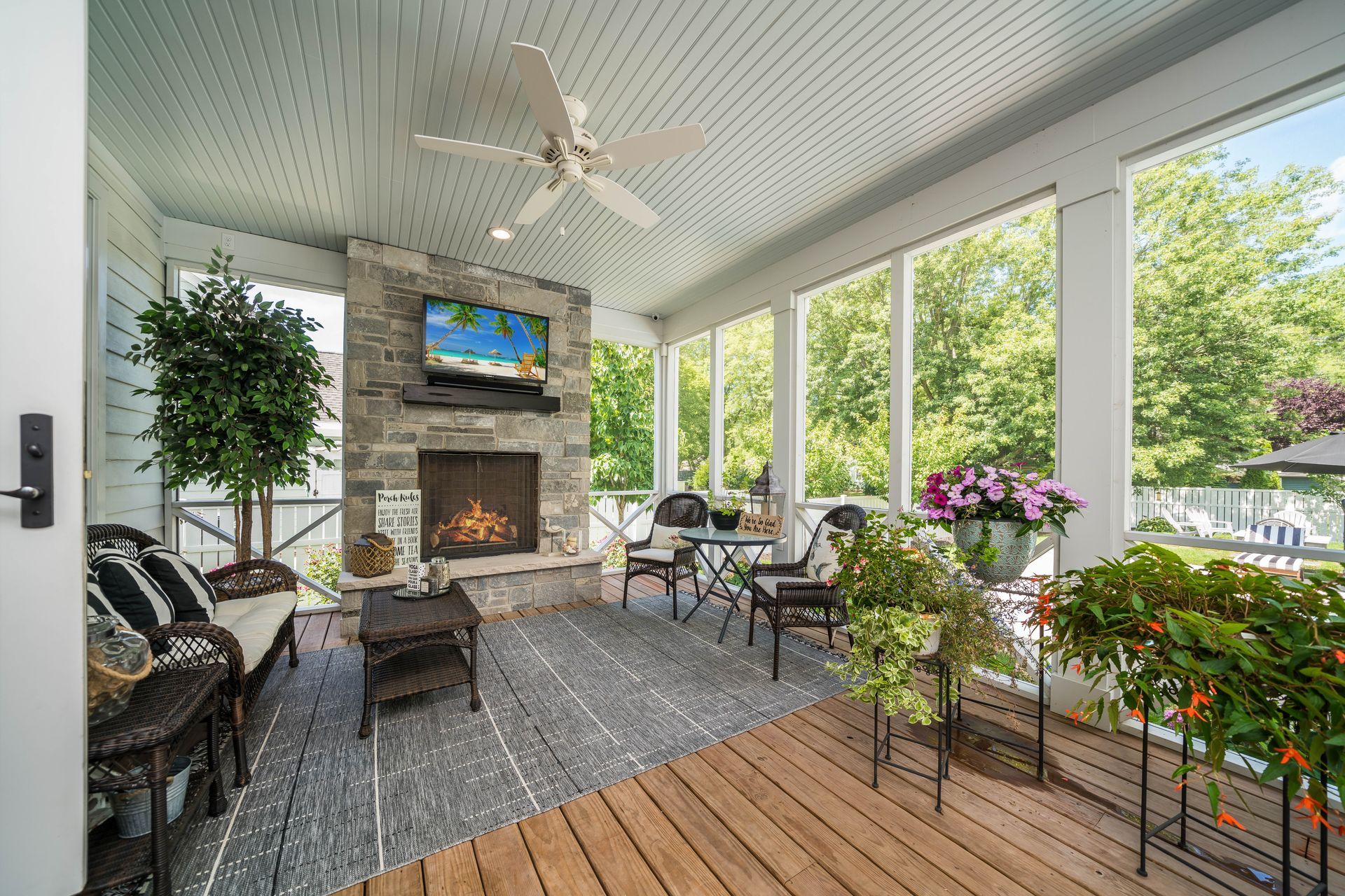 A screened in porch with a fireplace and television.
