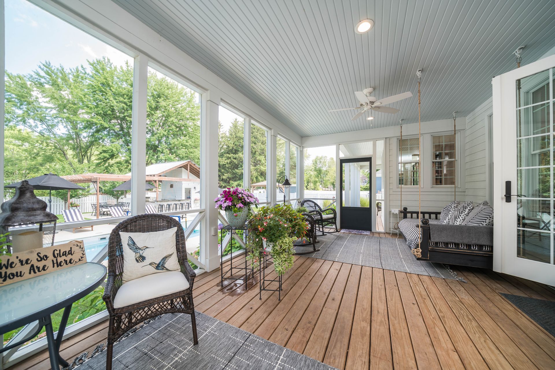 A screened in porch with a lot of windows and a ceiling fan.
