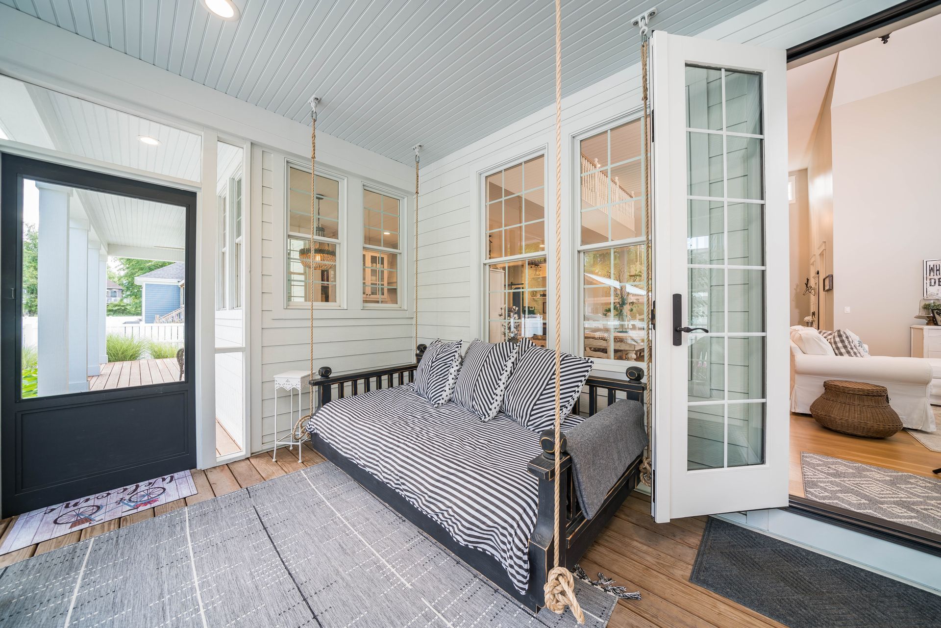 A porch with a swing and a couch hanging from the ceiling.