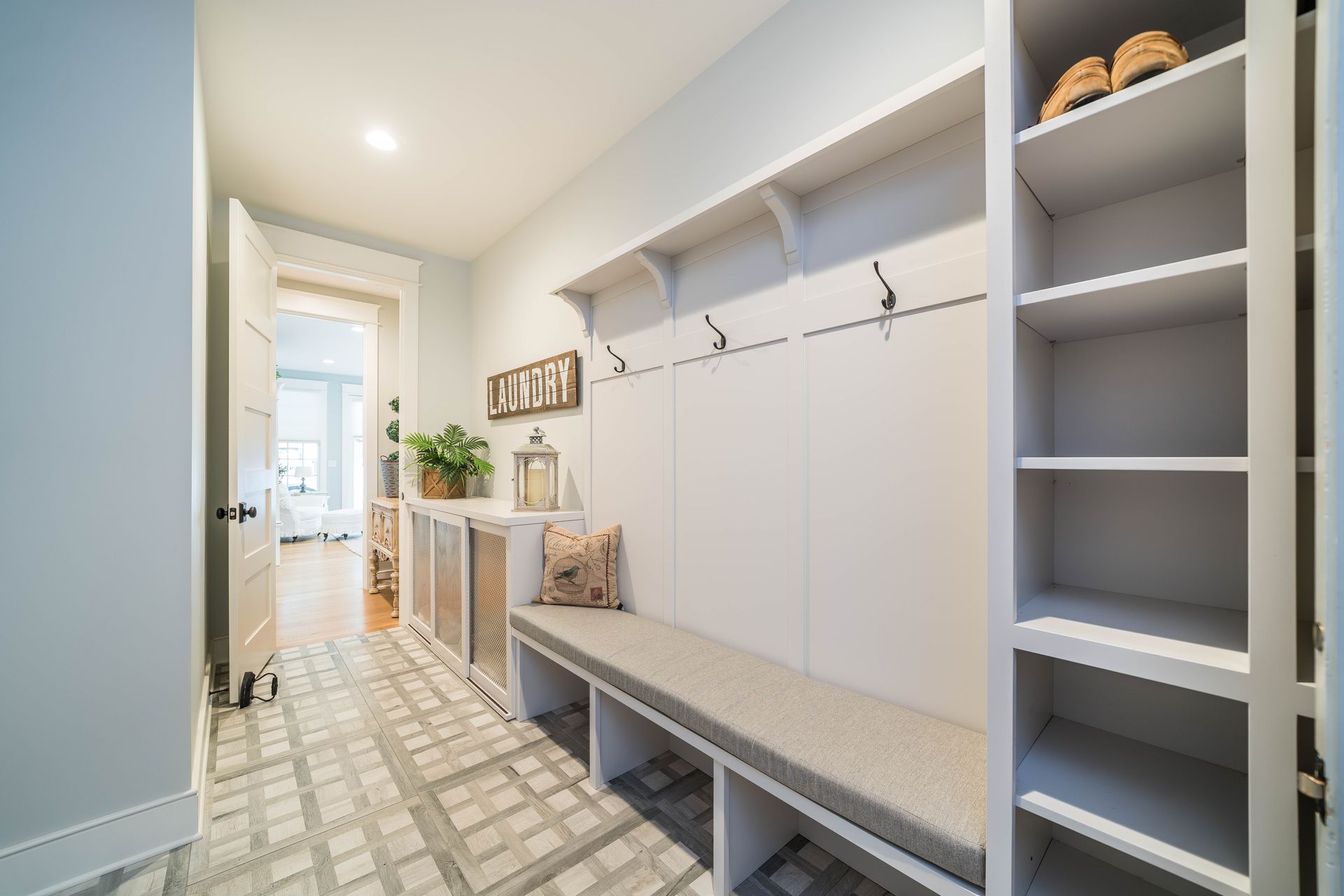 A hallway with a bench and shelves in a house.