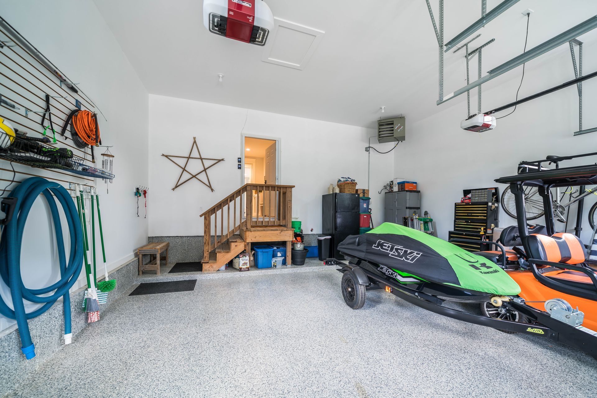 A jet ski is parked in a garage next to a boat.