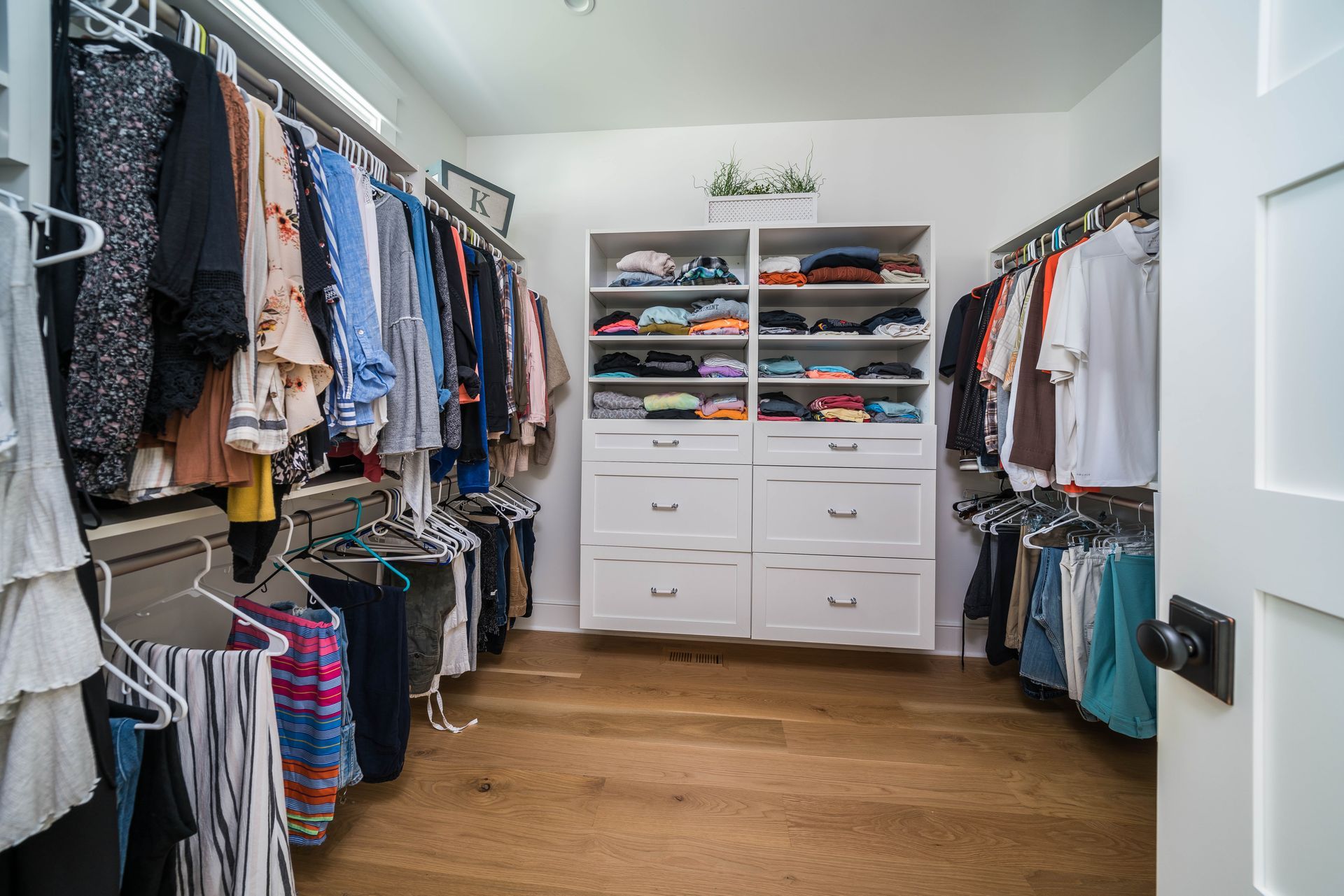 A walk in closet filled with lots of clothes and drawers.
