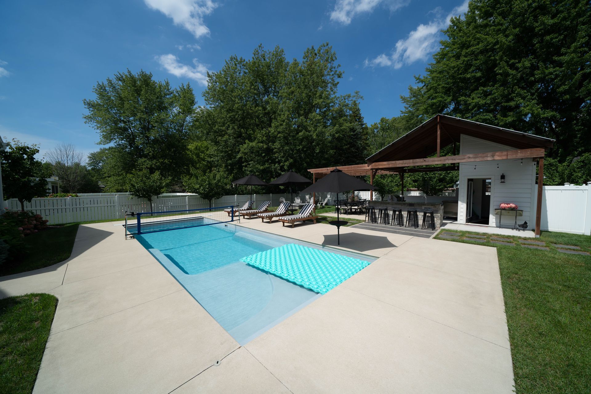 There is a large swimming pool in the backyard of a house.