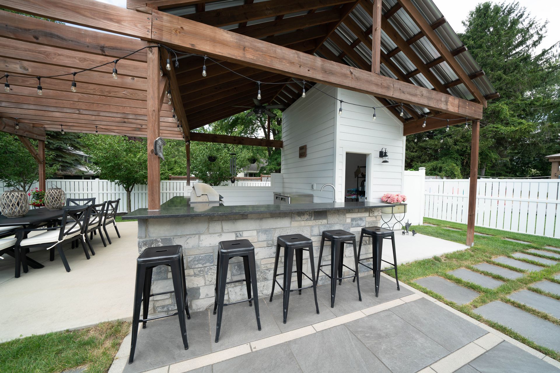 A patio with a bar and stools under a pergola