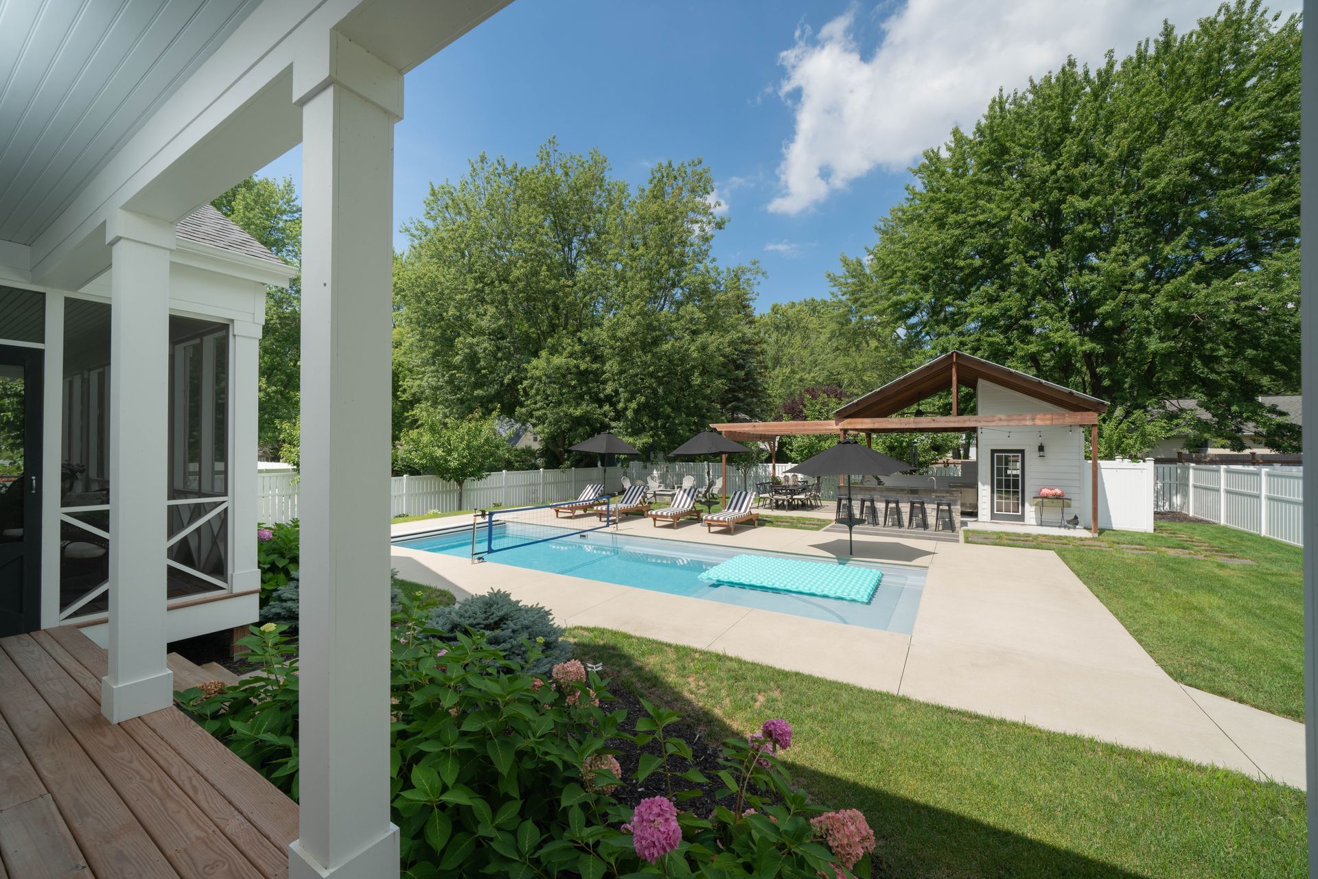 There is a large swimming pool in the backyard of a house.