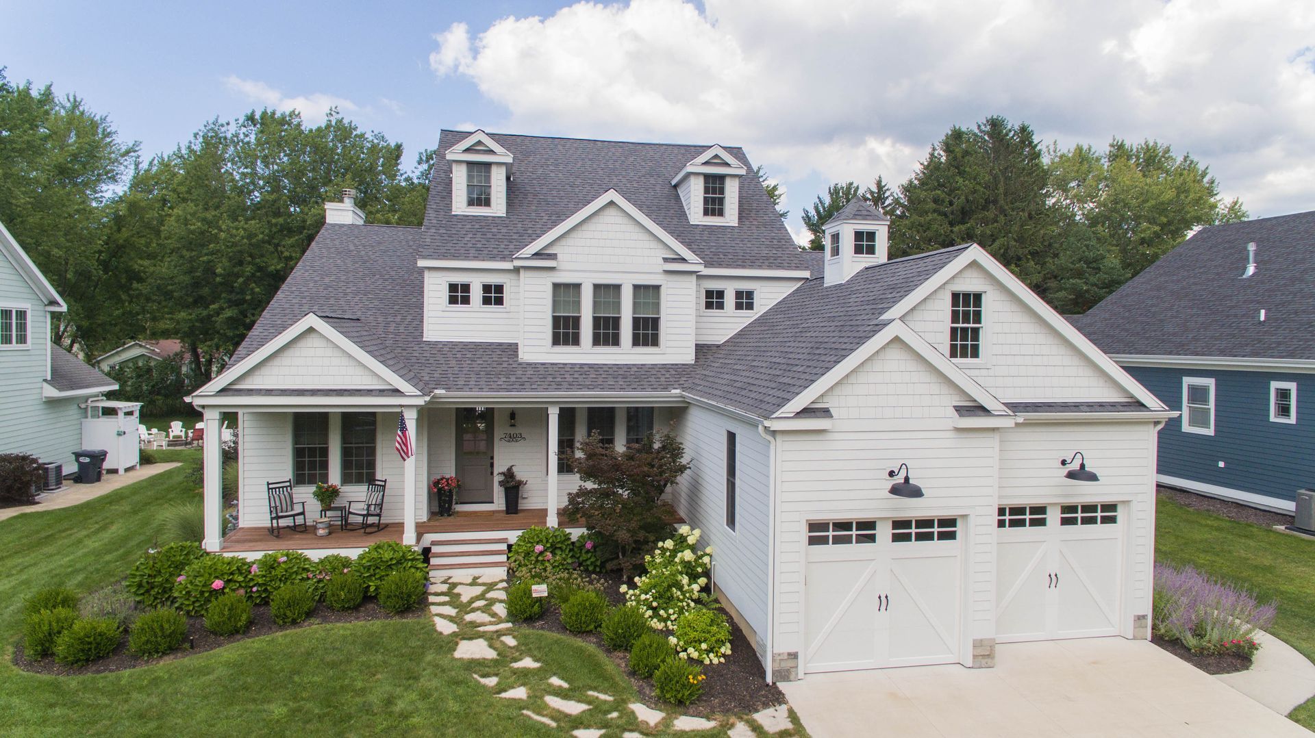 An aerial view of a large white house with a gray roof