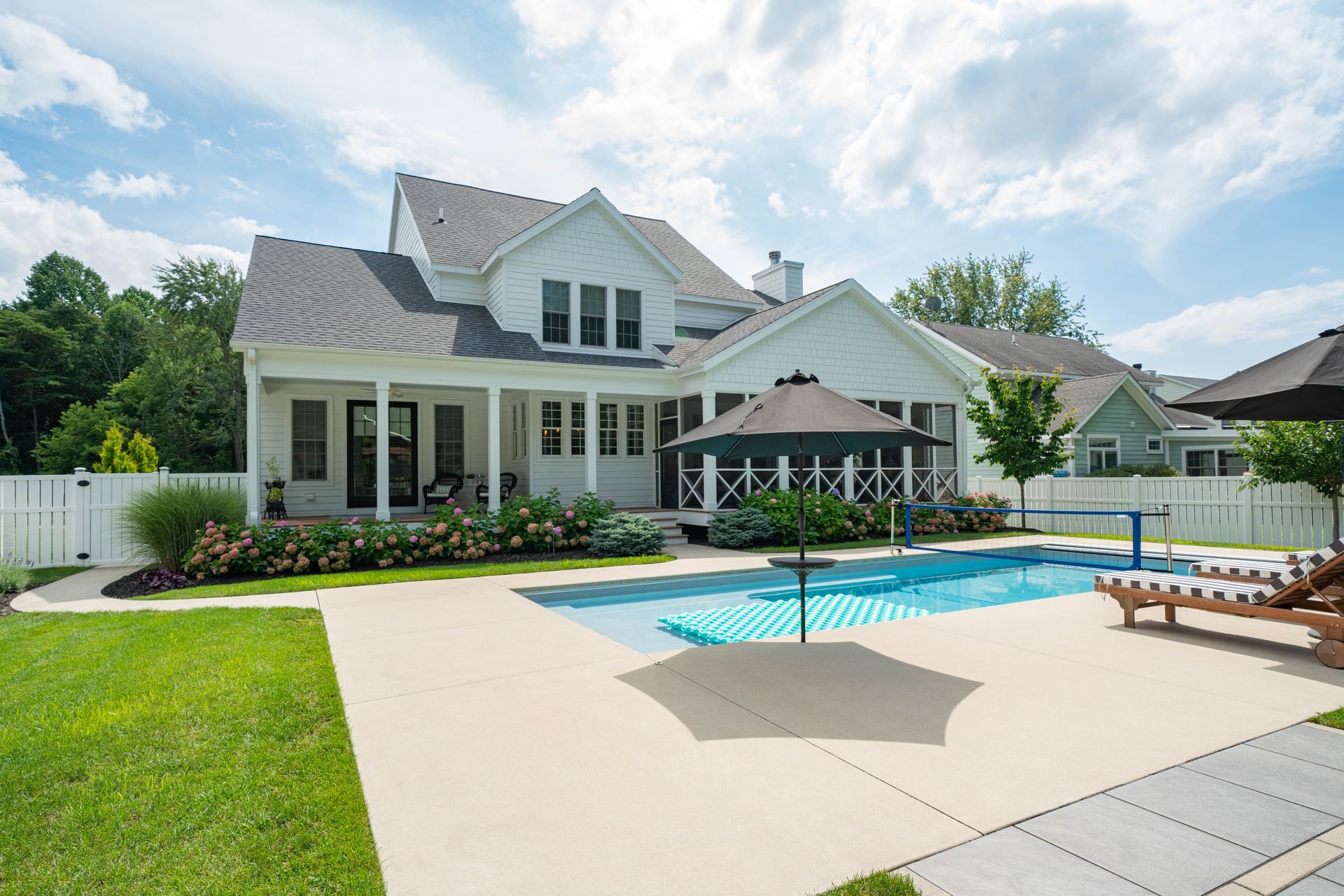 A large white house with a large swimming pool in the backyard.
