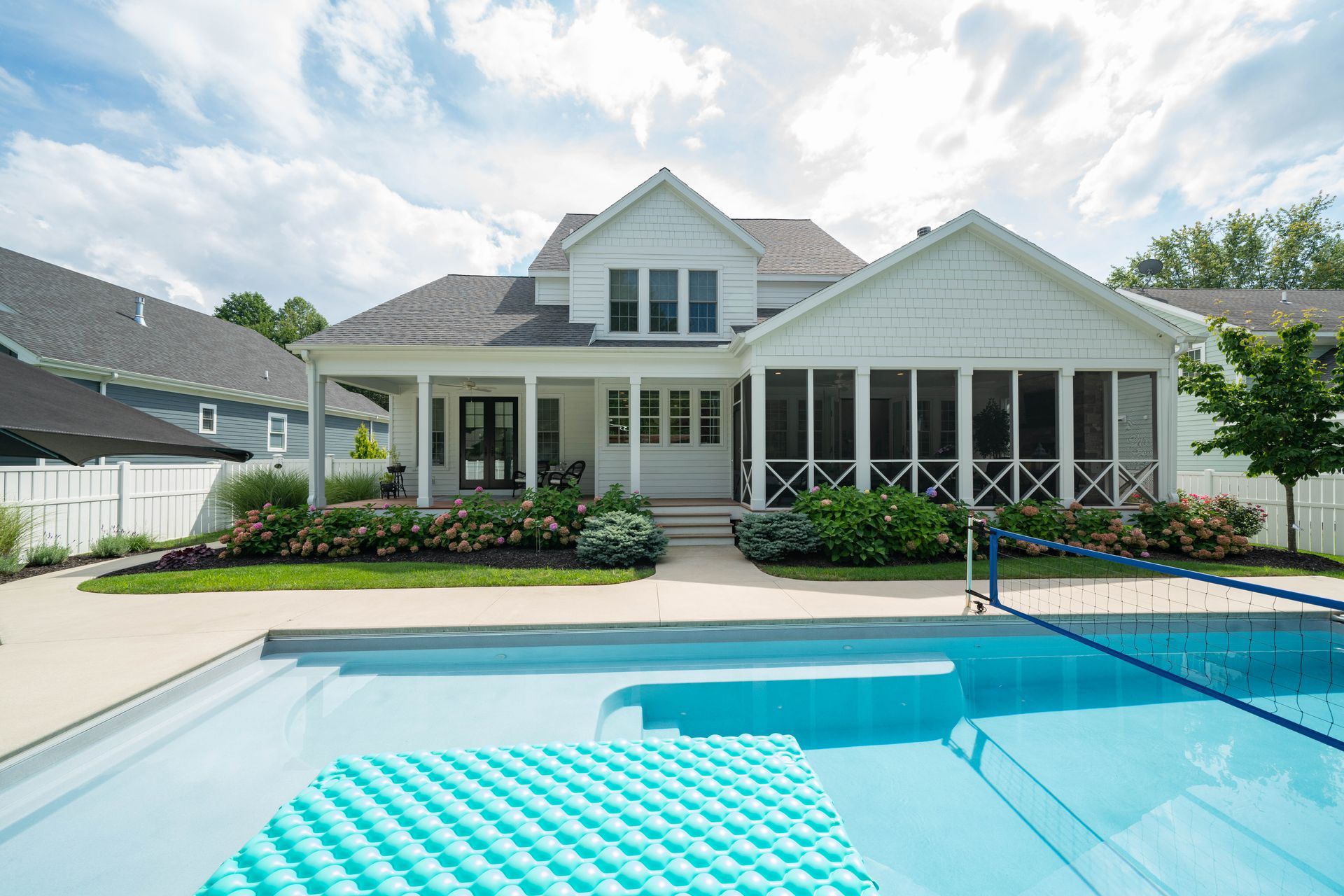 A large white house with a screened in porch and a swimming pool in front of it.