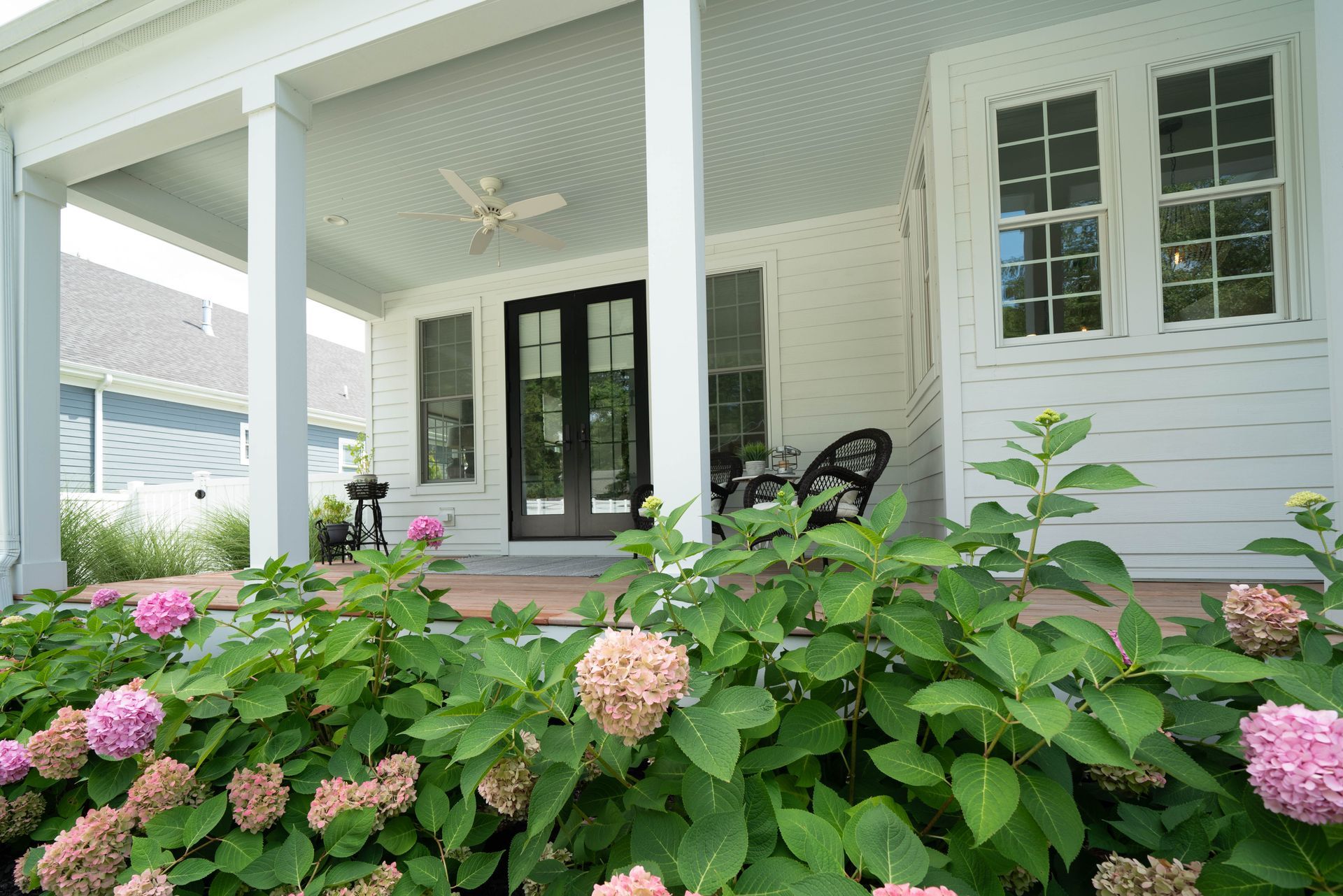 A white house with a porch and flowers in front of it
