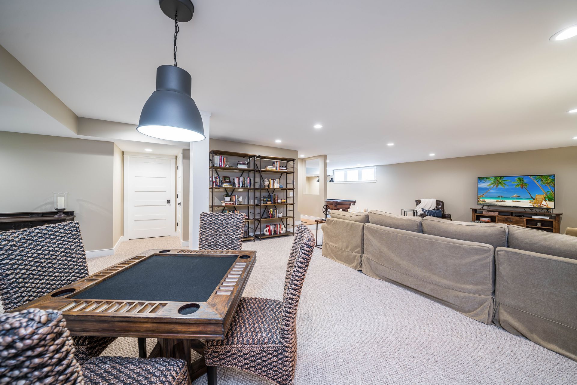 A basement with a table and chairs and a television.