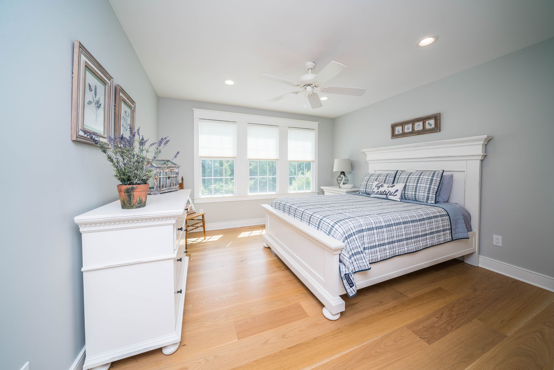 A bedroom with a bed , dresser , mirror and ceiling fan.