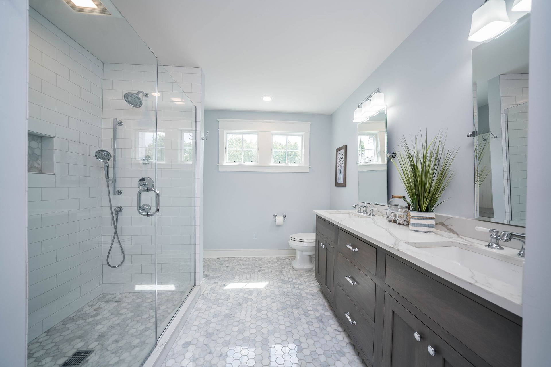 A bathroom with two sinks , a toilet , and a walk in shower.