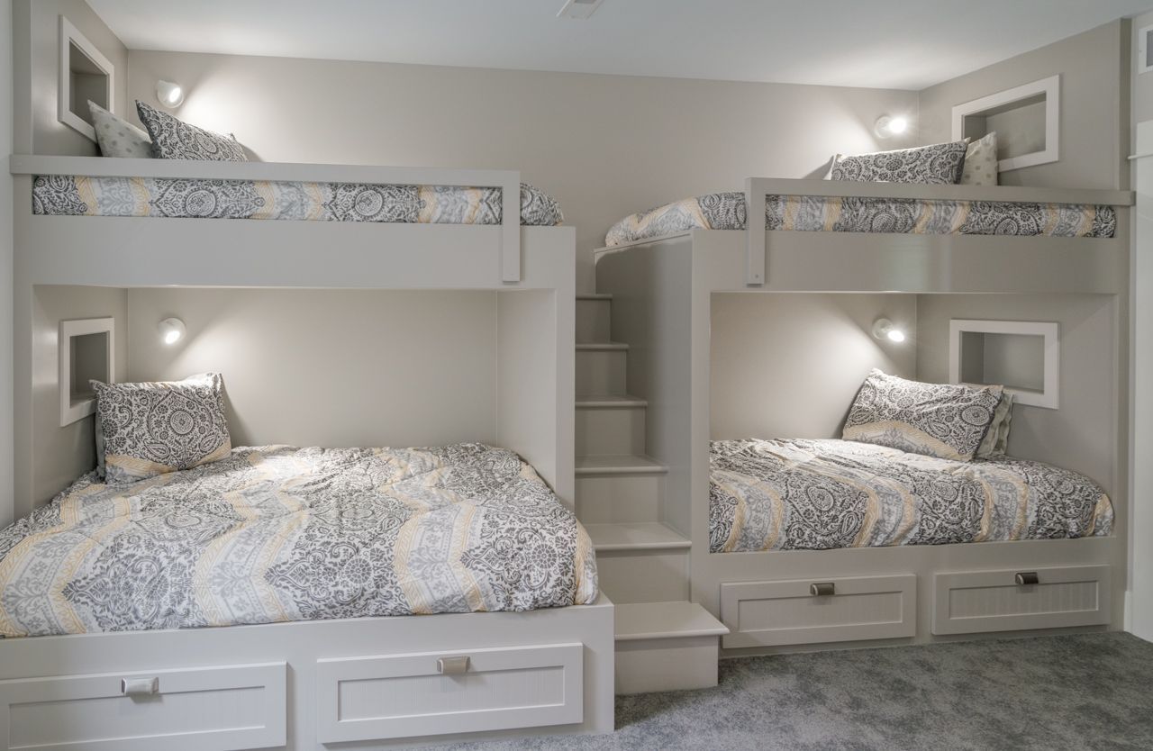 A bedroom with three bunk beds and stairs.