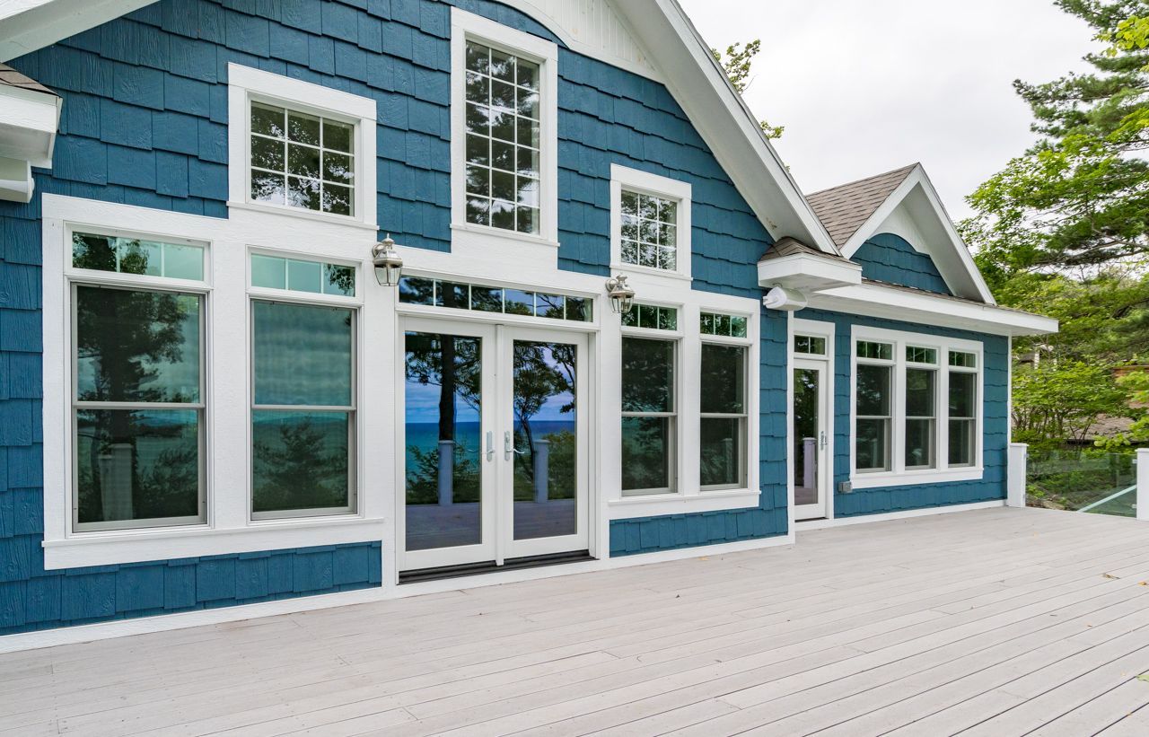 A blue and white house with a large deck in front of it.