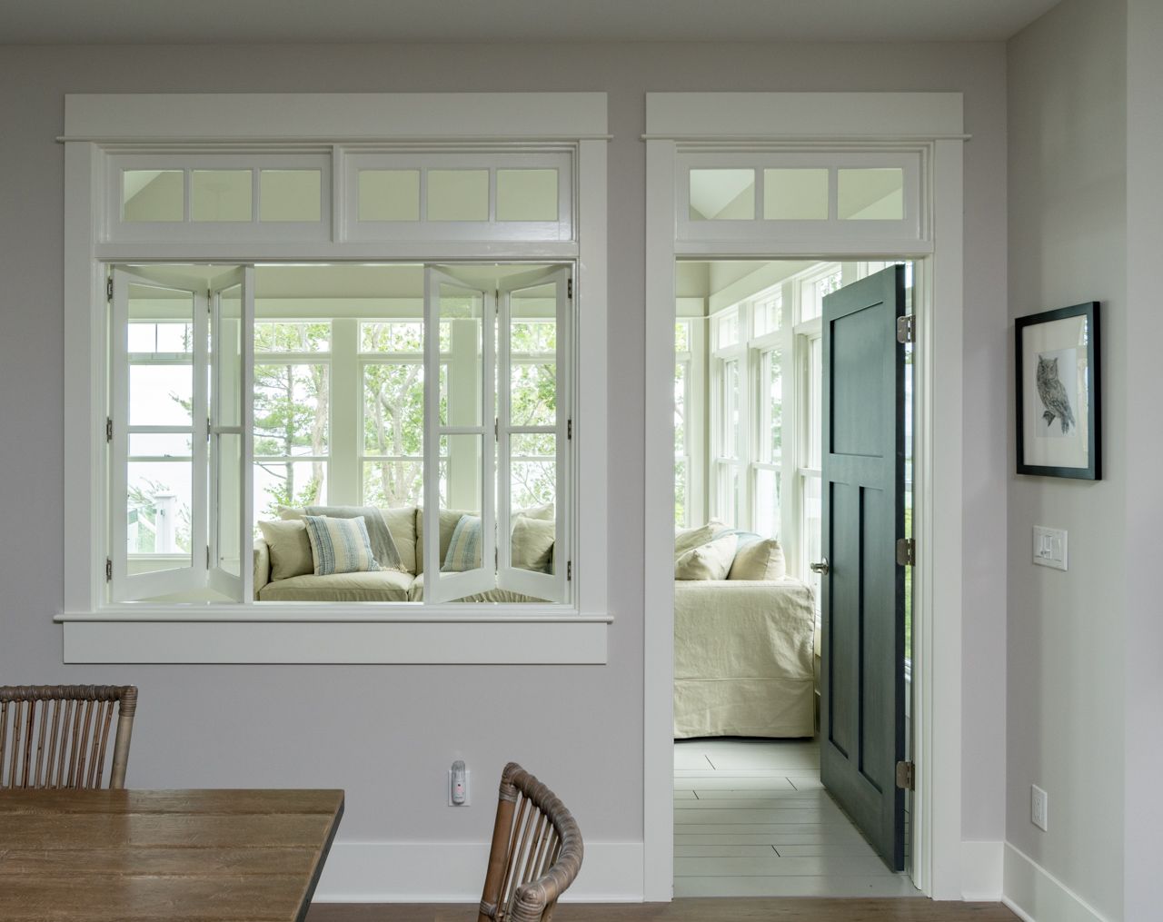A dining room with a table and chairs and a door leading to a living room