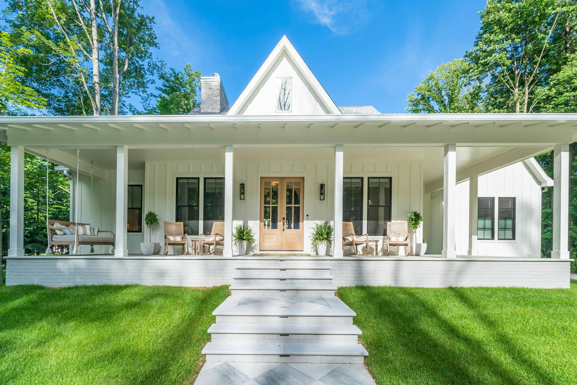 A white house with a large porch and stairs leading to it.