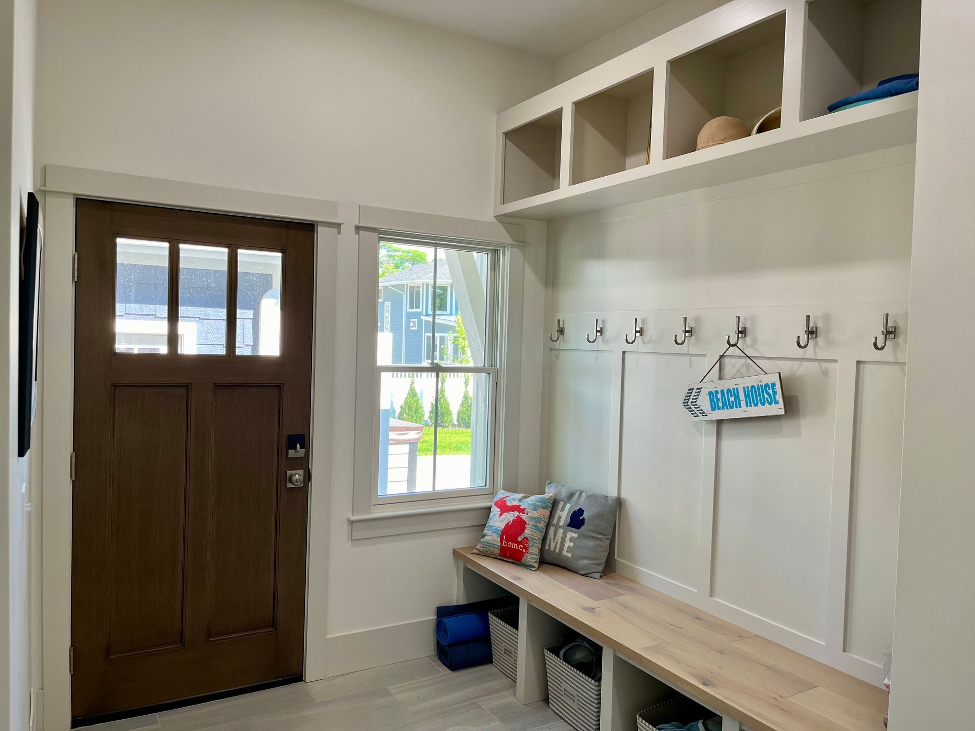A mud room with a bench and hooks in a house.