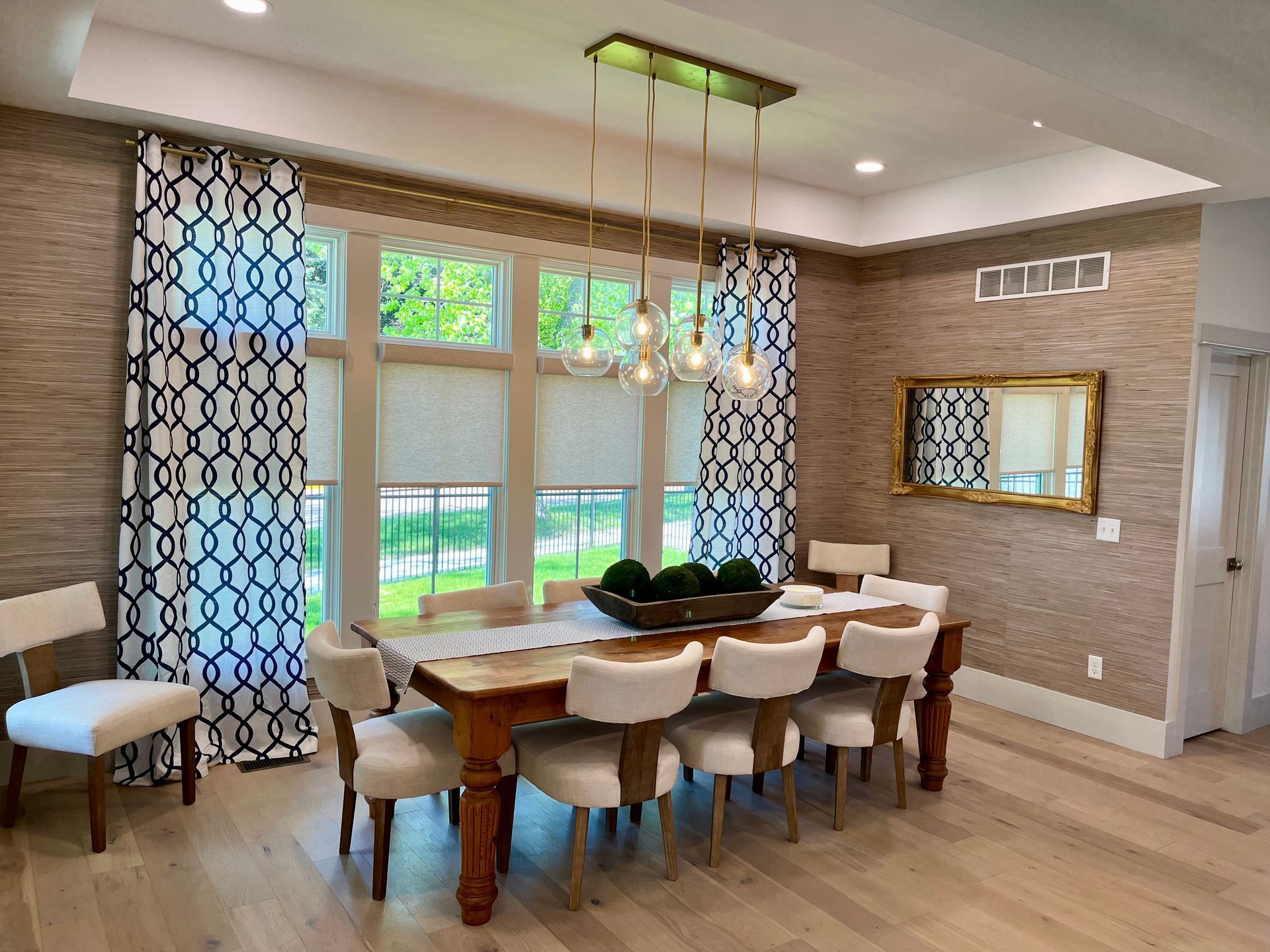 A dining room with a table and chairs and a mirror.