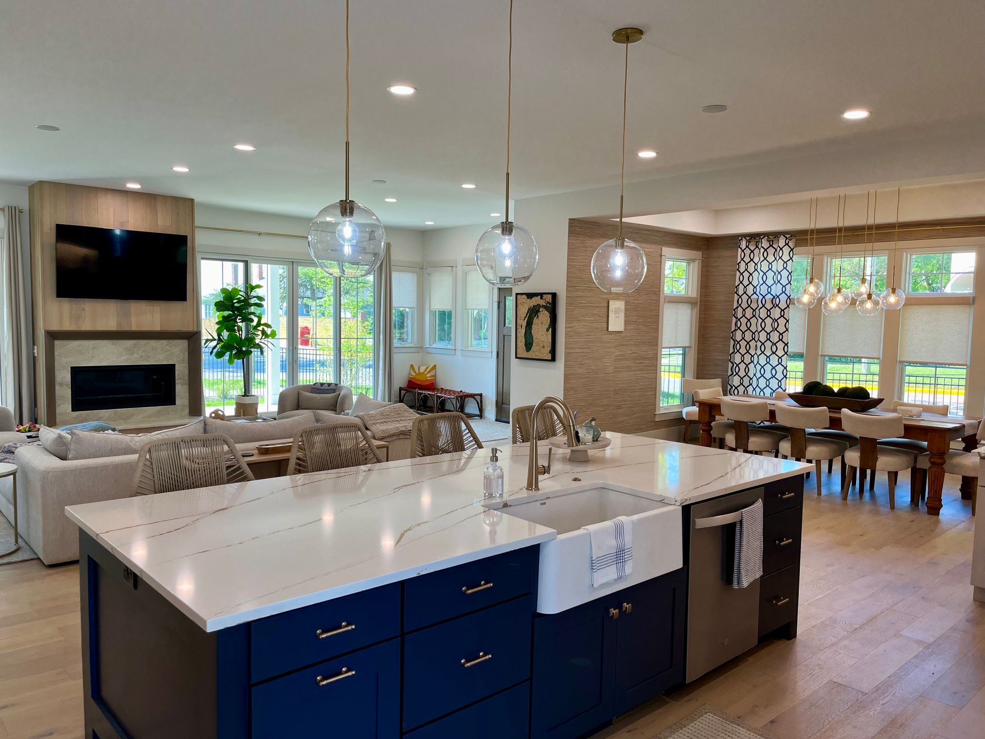 A kitchen with blue cabinets , white counter tops , a sink , and a large island.