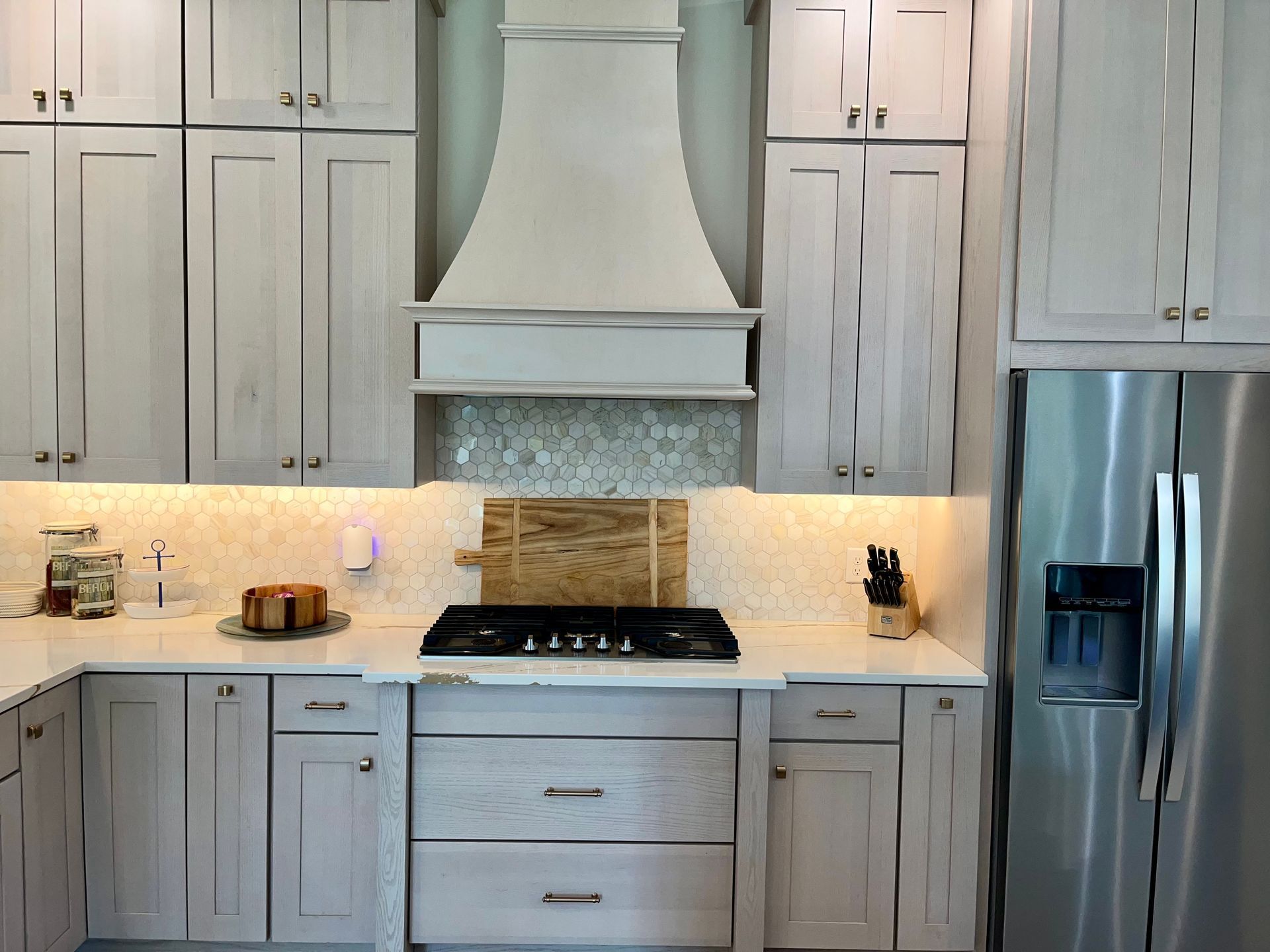 A kitchen with white cabinets and a stainless steel refrigerator