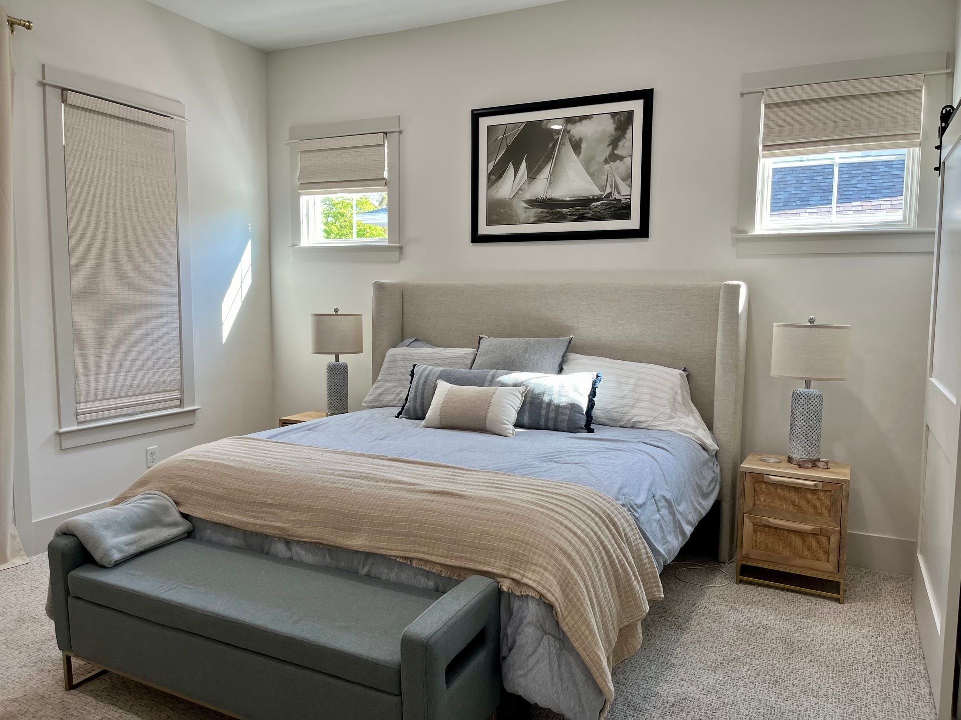 A bedroom with a king size bed , nightstands , lamps , and a bench.