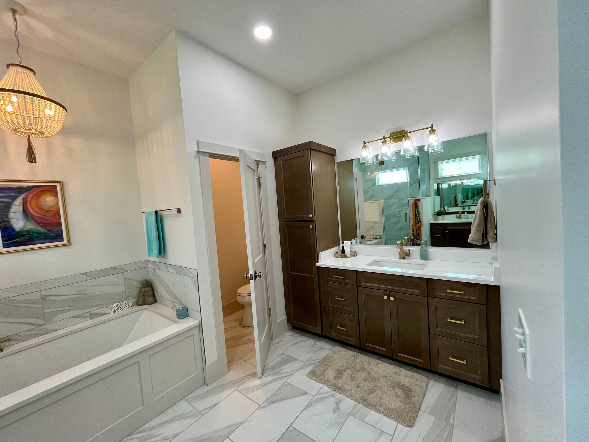 A bathroom with two sinks , a tub , and a chandelier.