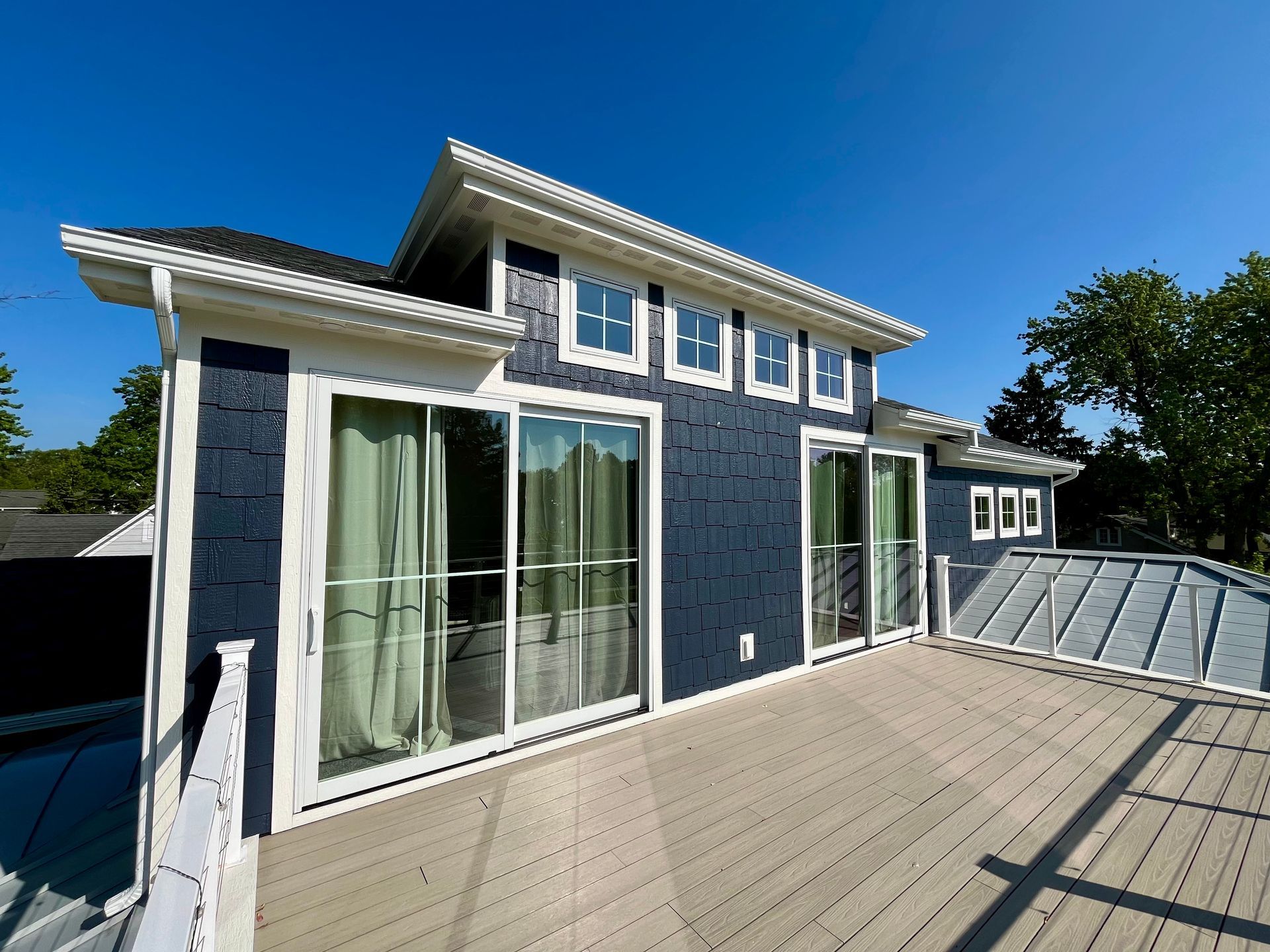 The back of a house with a large deck and sliding glass doors.