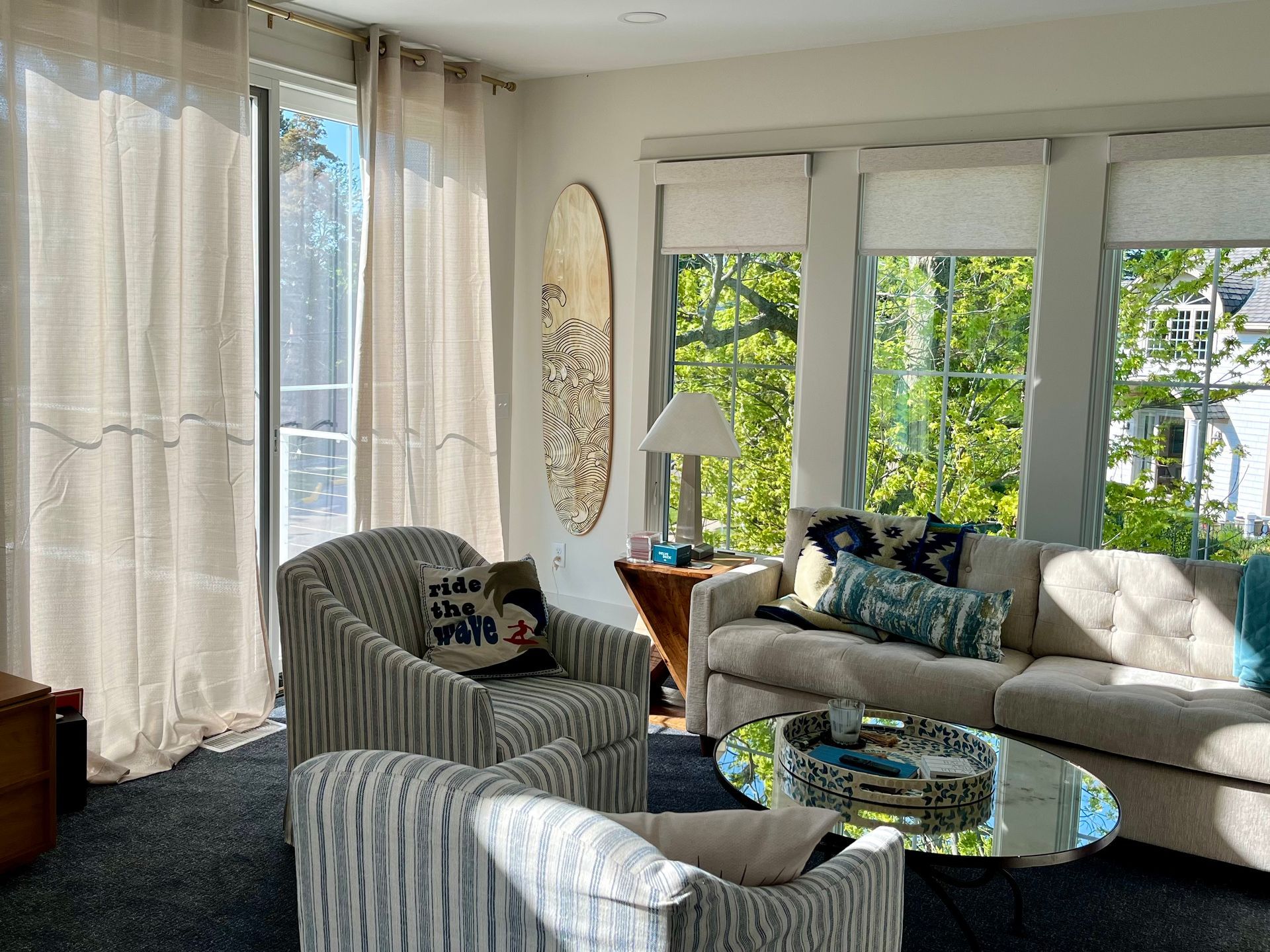 A living room with a couch and chairs and a surfboard on the wall