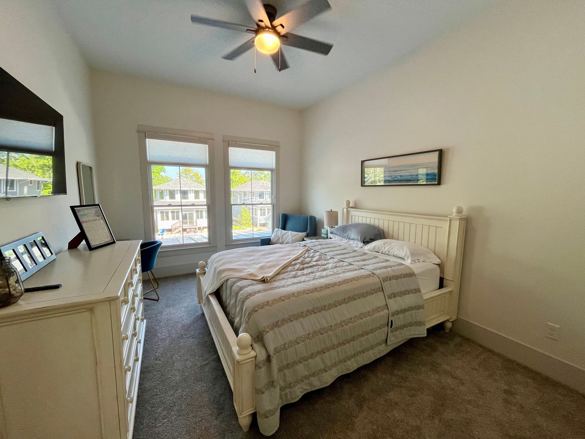 A bedroom with a bed , dresser , mirror and ceiling fan.