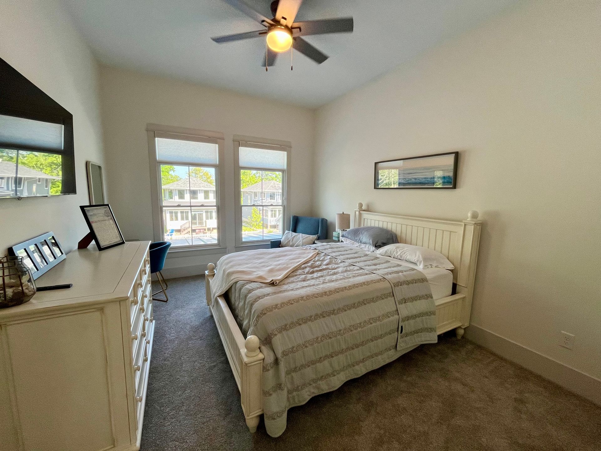 A bedroom with a bed , dresser , mirror and ceiling fan.