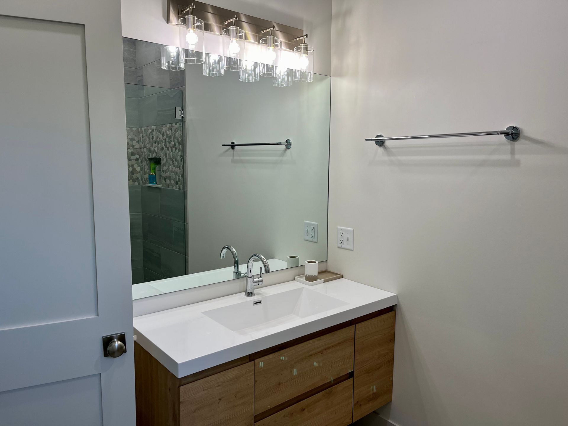 A bathroom with a sink , mirror and towel rack.