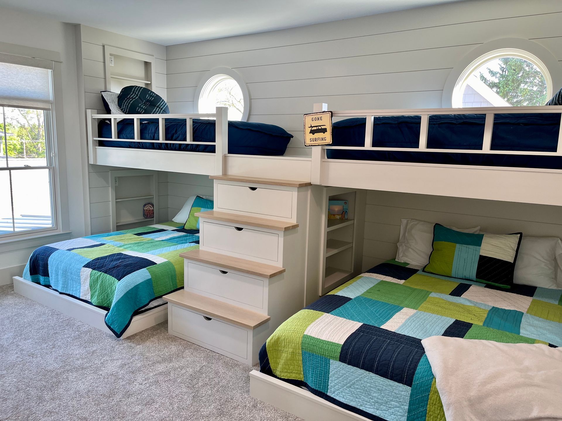 A bedroom with three bunk beds and stairs leading up to them.