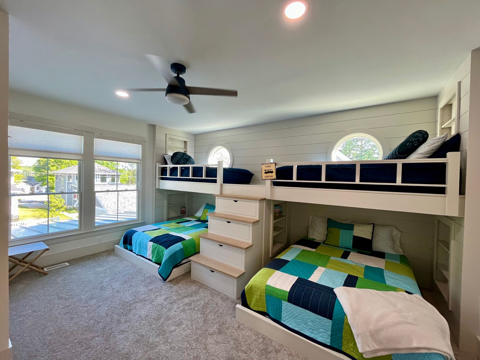 A bedroom with three bunk beds and a ceiling fan.