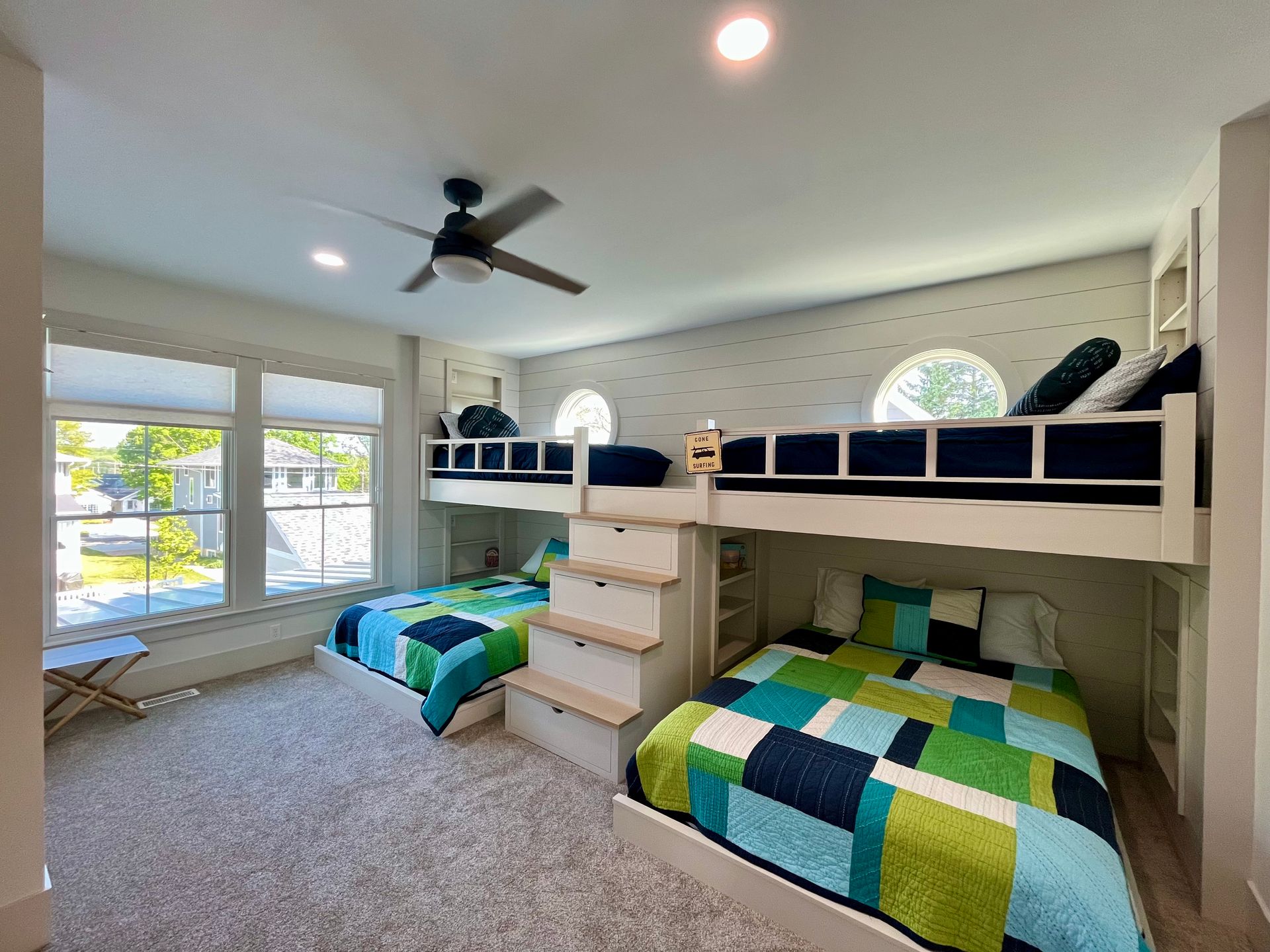 A bedroom with three bunk beds and a ceiling fan.
