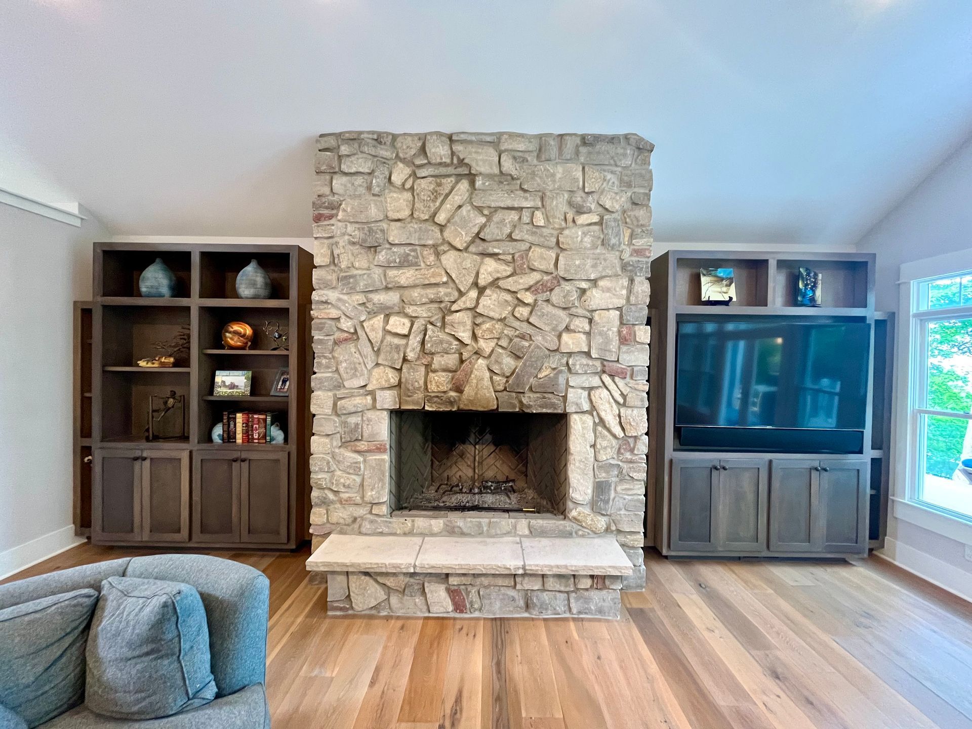 A living room with a stone fireplace and a flat screen tv.