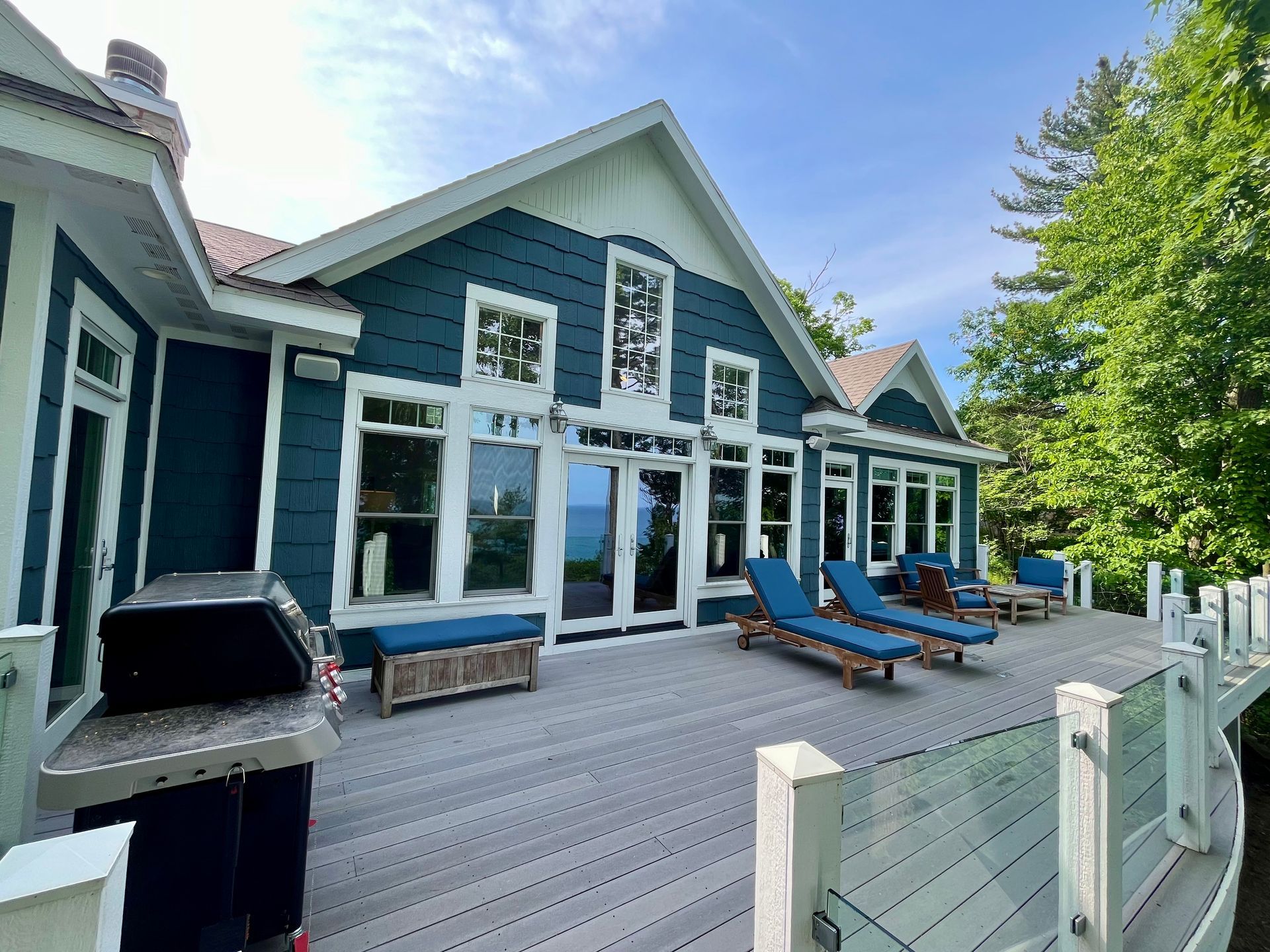 A large blue and white house with a large deck.