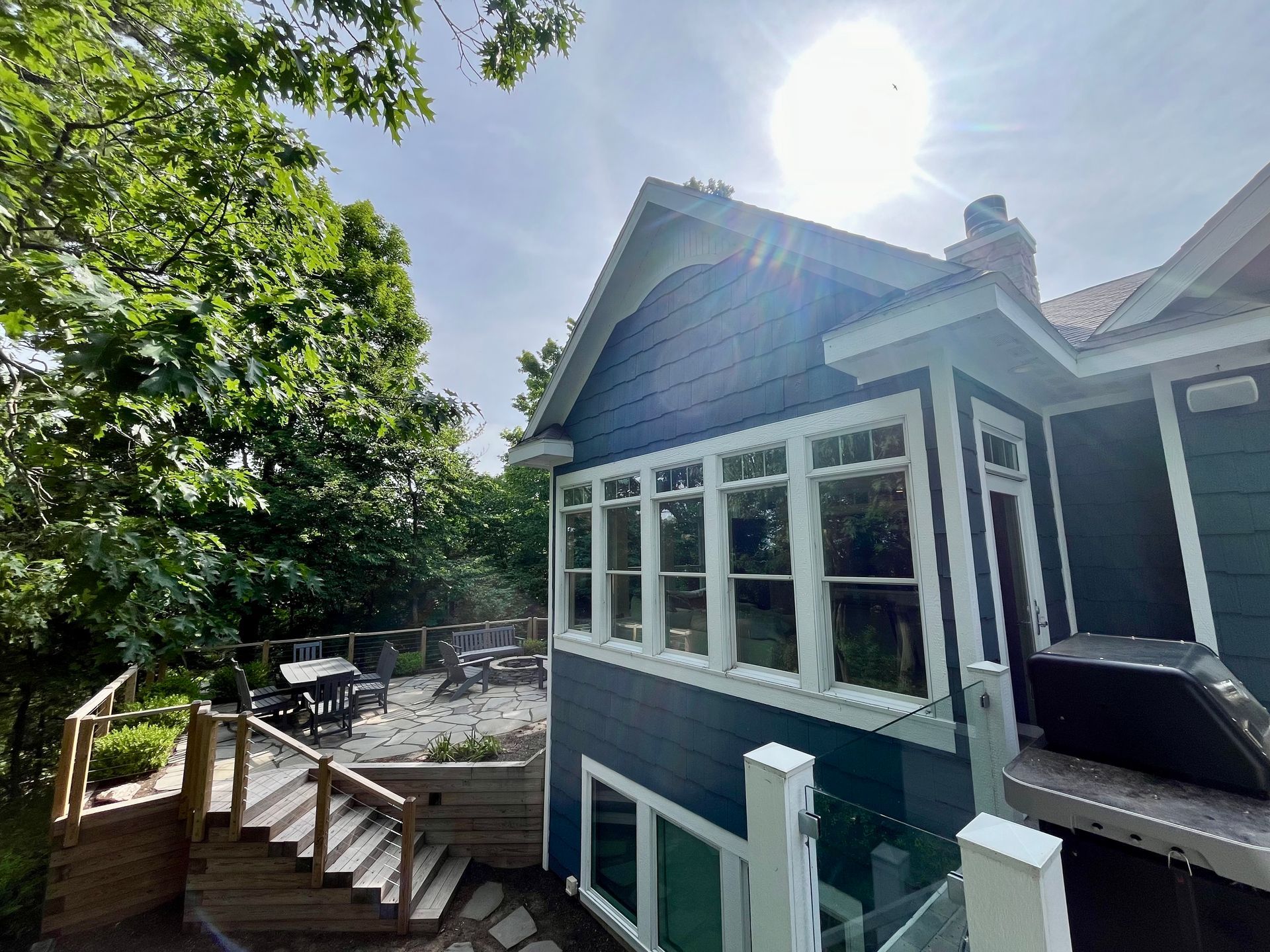 A blue house with a hot tub in the backyard.
