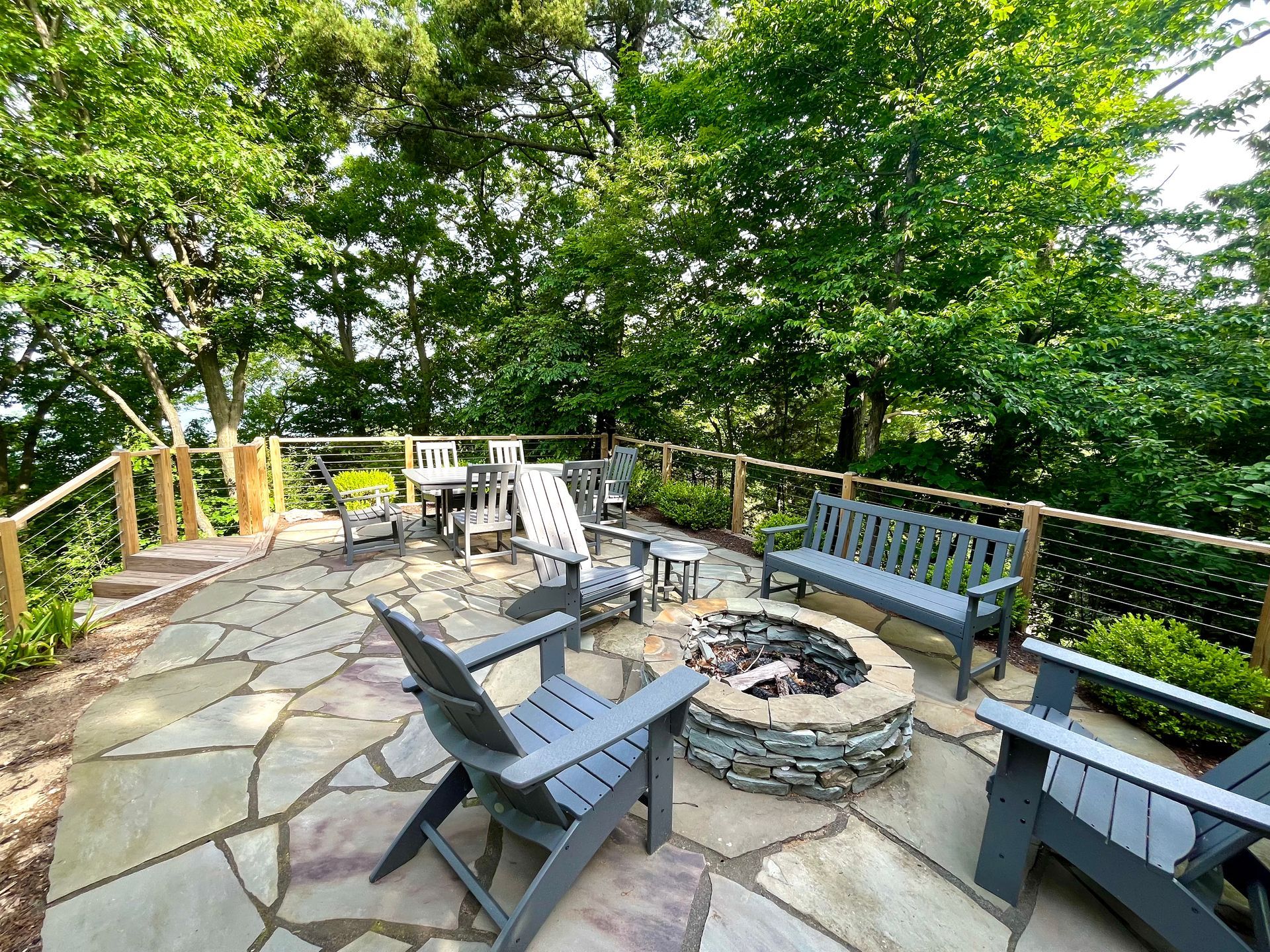 There is a fire pit on the patio with chairs and a bench.