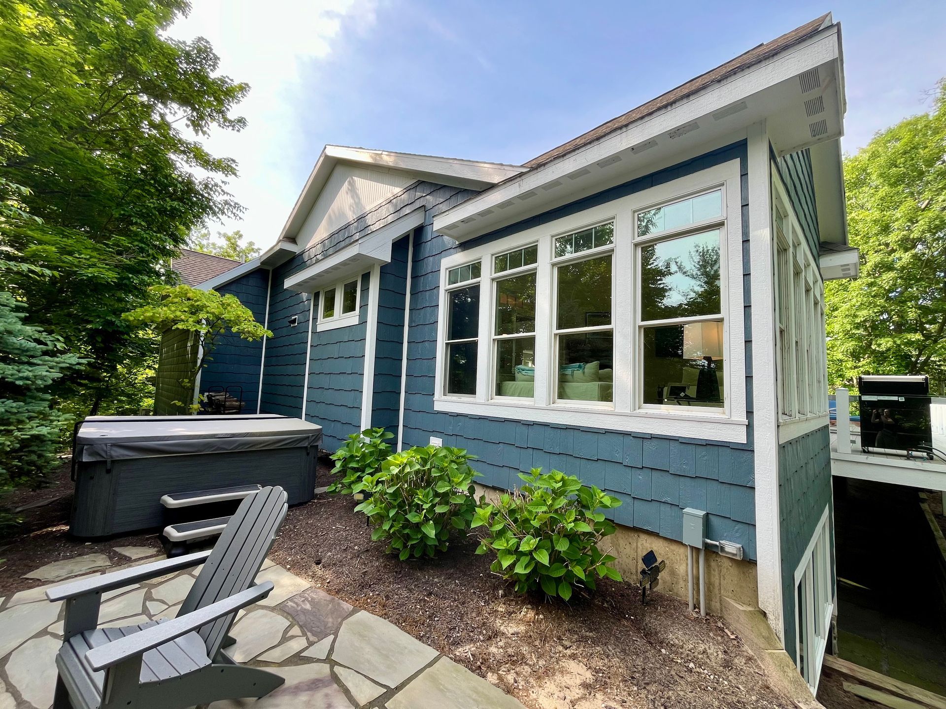 A blue house with a hot tub in the backyard.