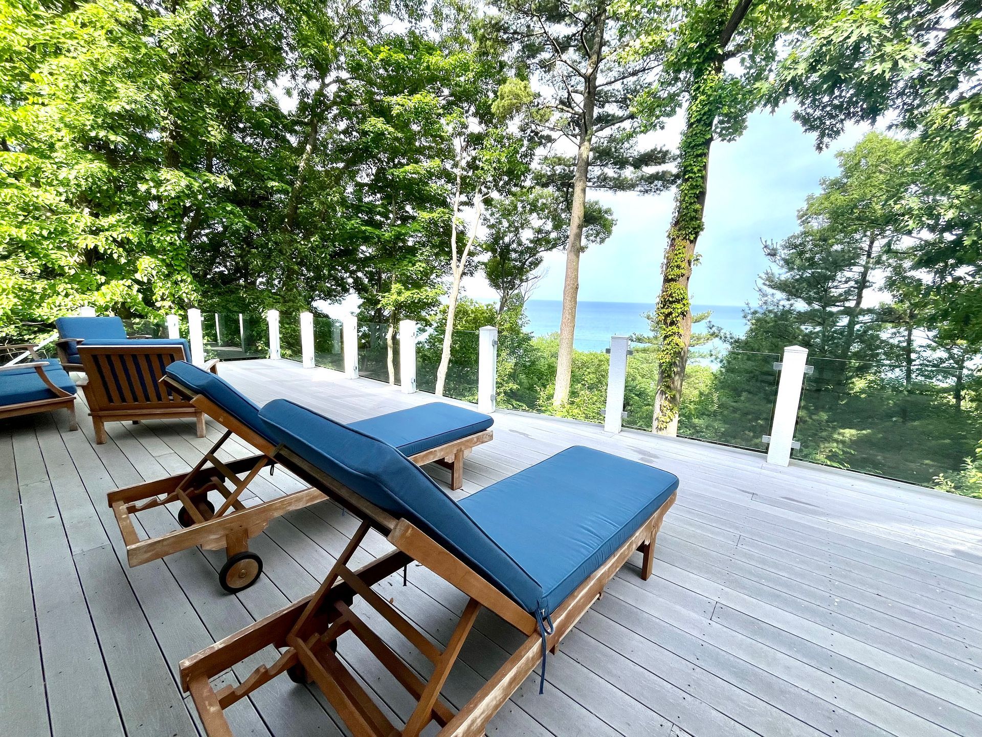 Two lounge chairs are sitting on a deck overlooking the ocean.