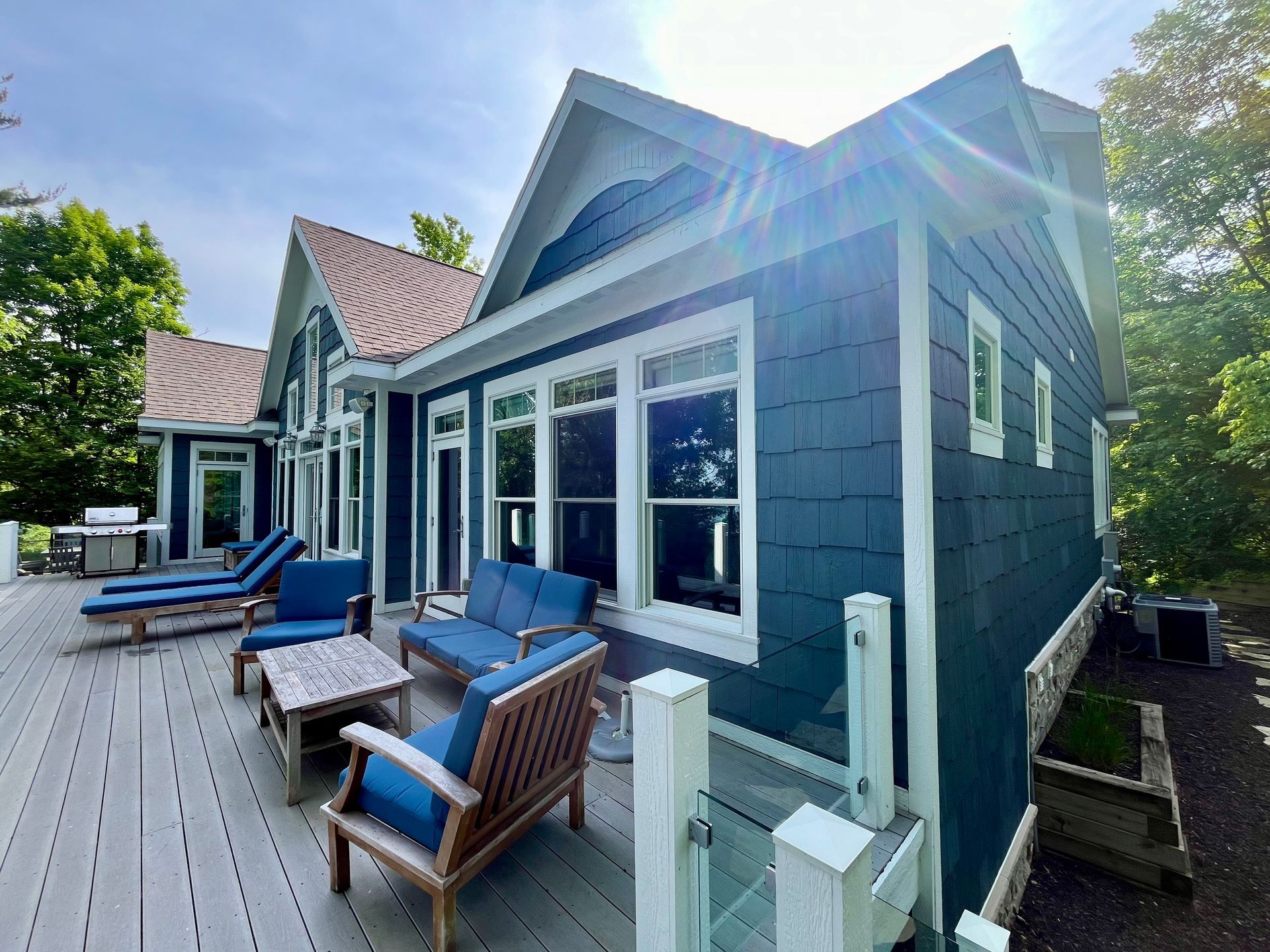 A blue house with a deck and patio furniture in front of it.