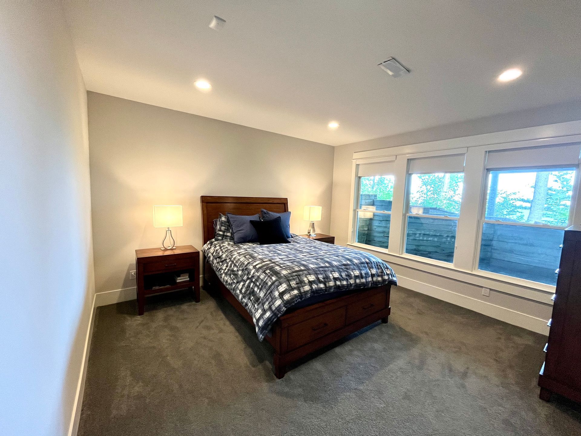 A bedroom with a king size bed , two nightstands , and two windows.