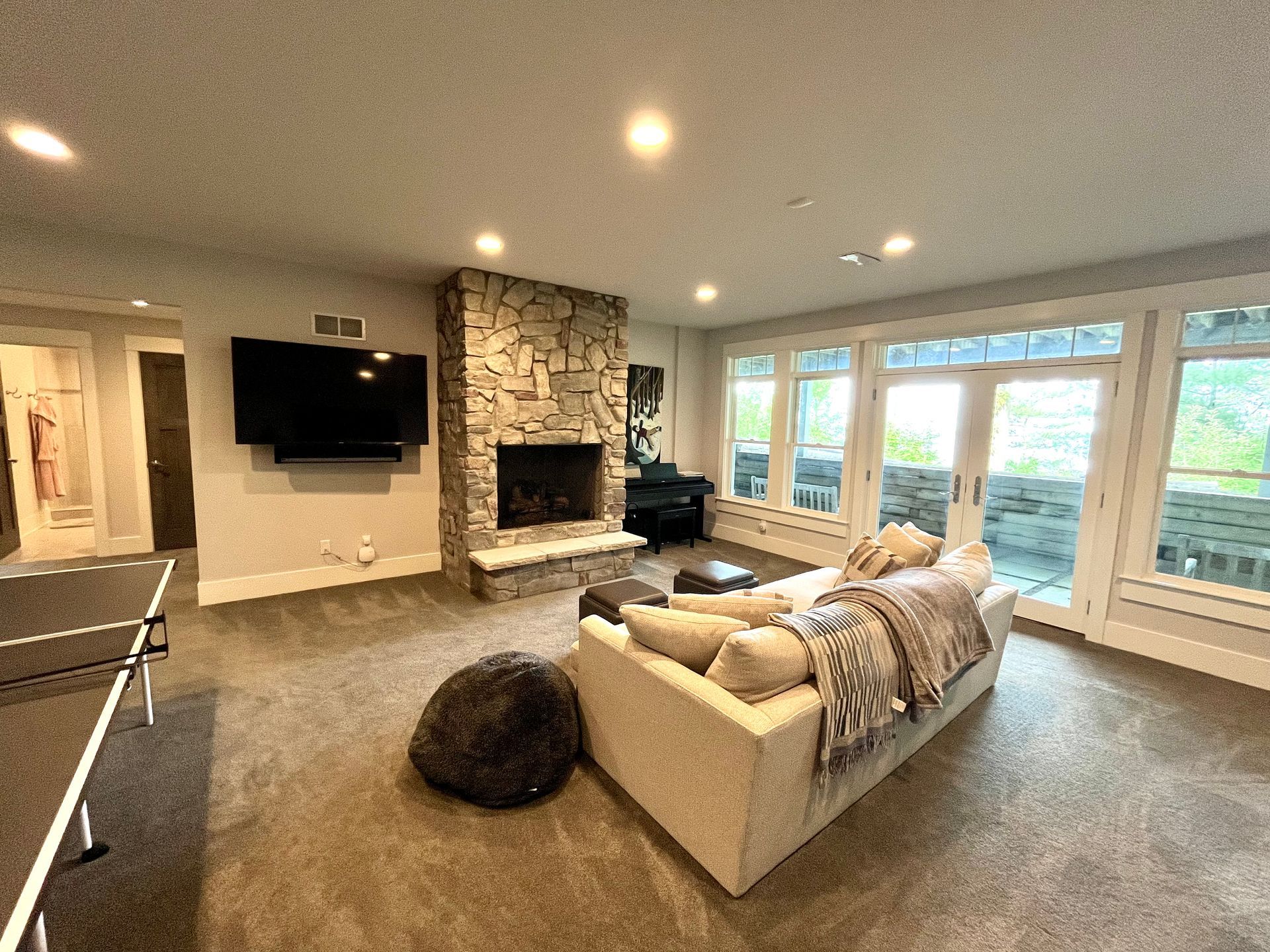 A living room with a couch , fireplace , television and ping pong table.