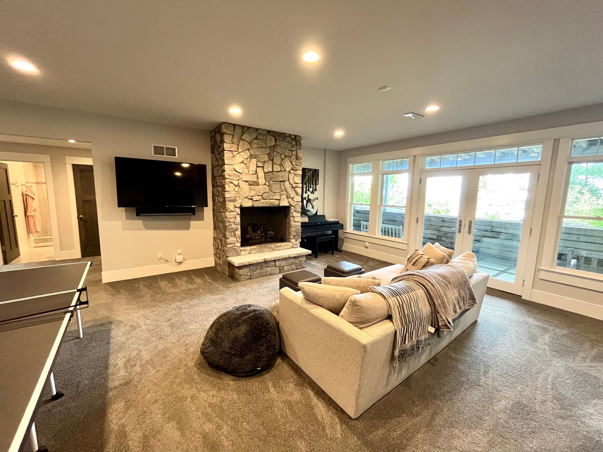 A living room with a couch , fireplace , television and ping pong table.