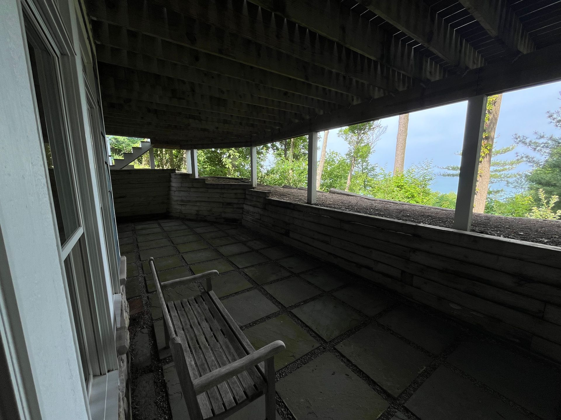 A porch with a bench and a view of the ocean.