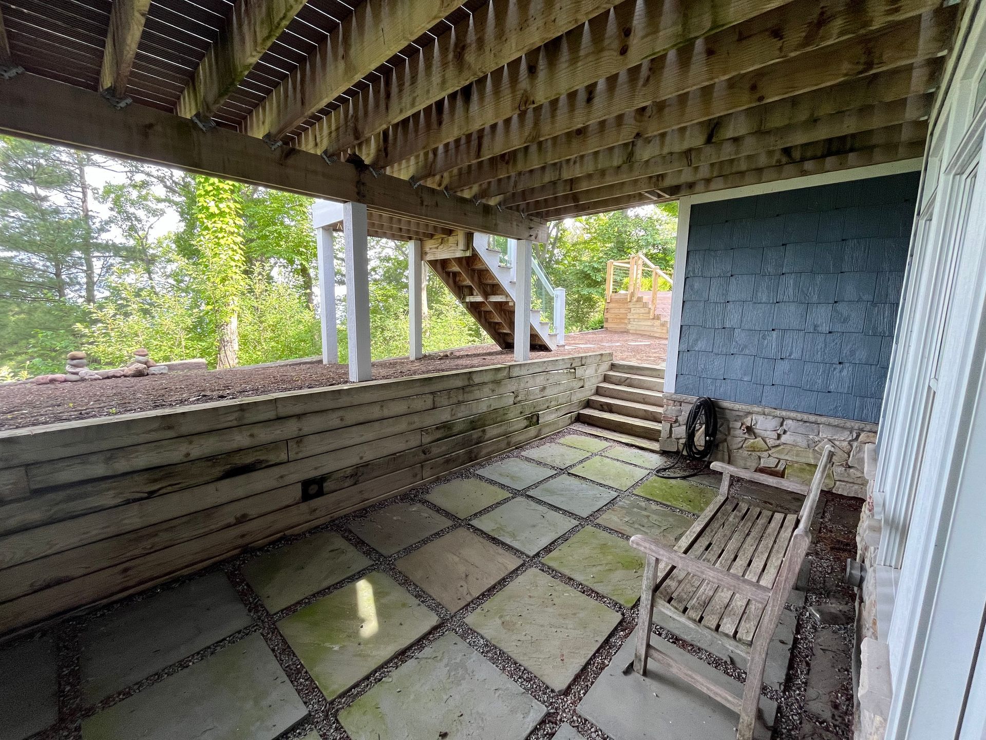 A porch with a table and chairs under a wooden roof.