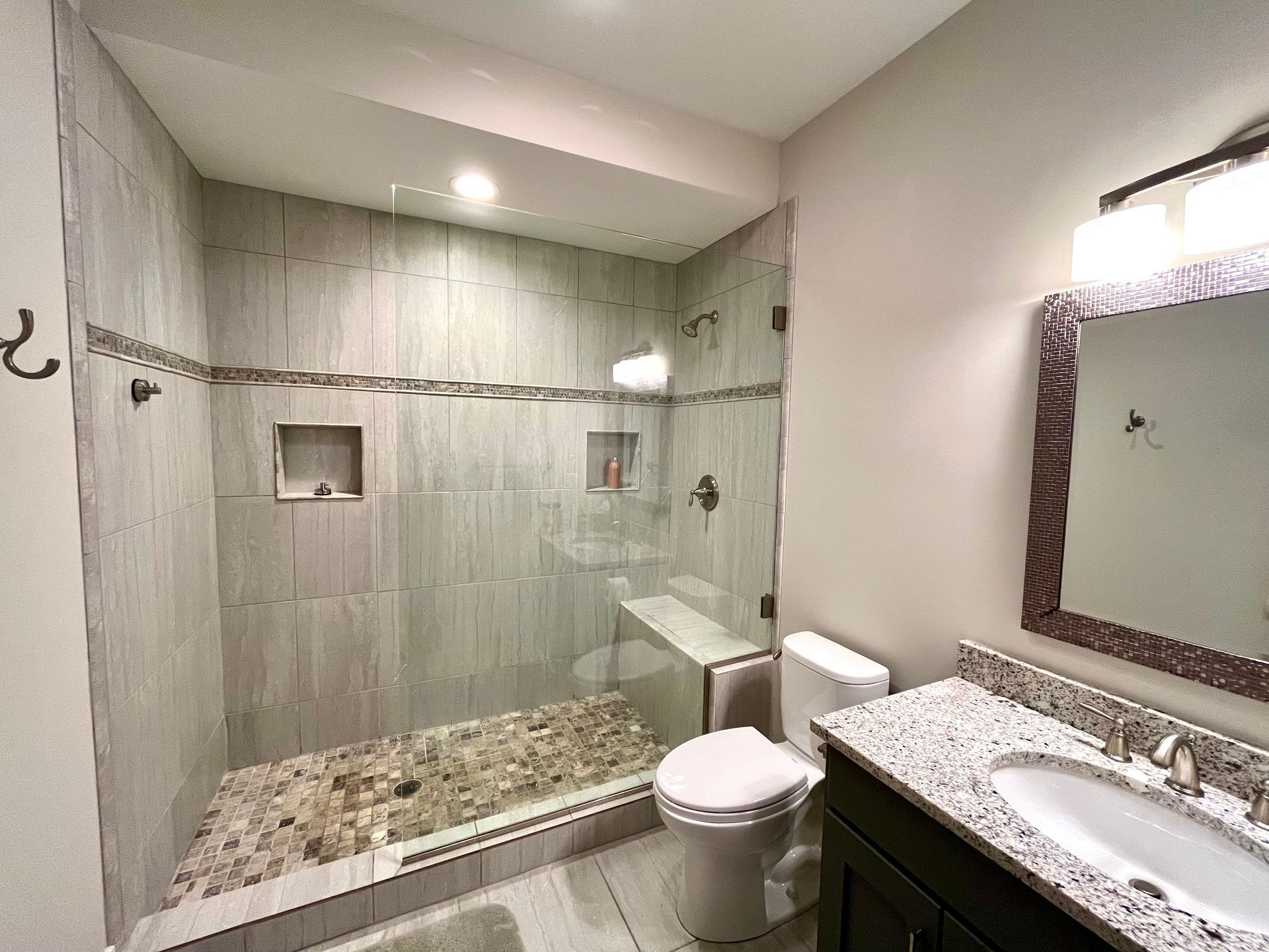 A bathroom with a toilet , sink and walk in shower.